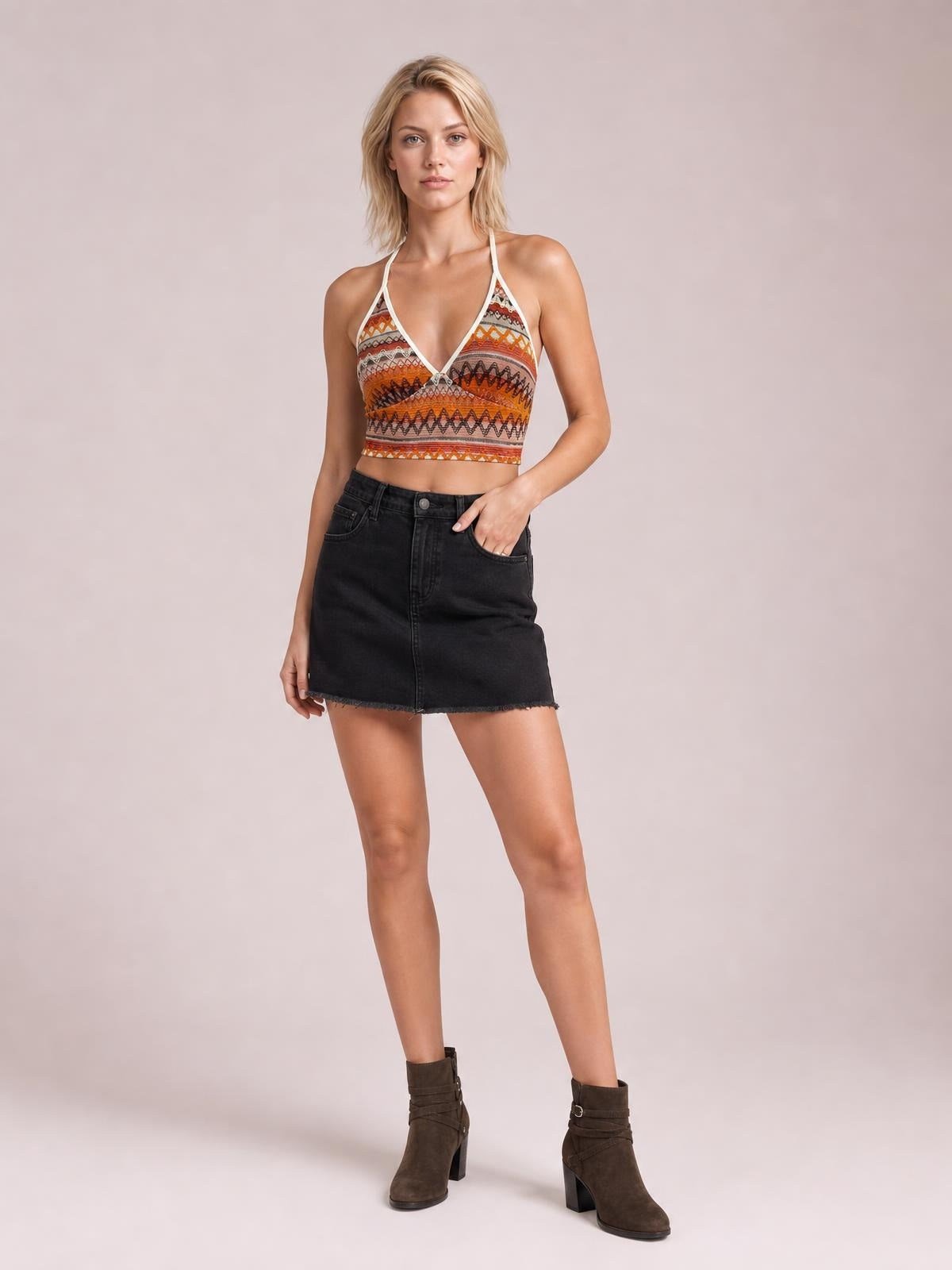 A model poses in a multicolored patterned halter neck short cami with a V-neckline, tie detail, slim straps, and a fitted cropped silhouette.
