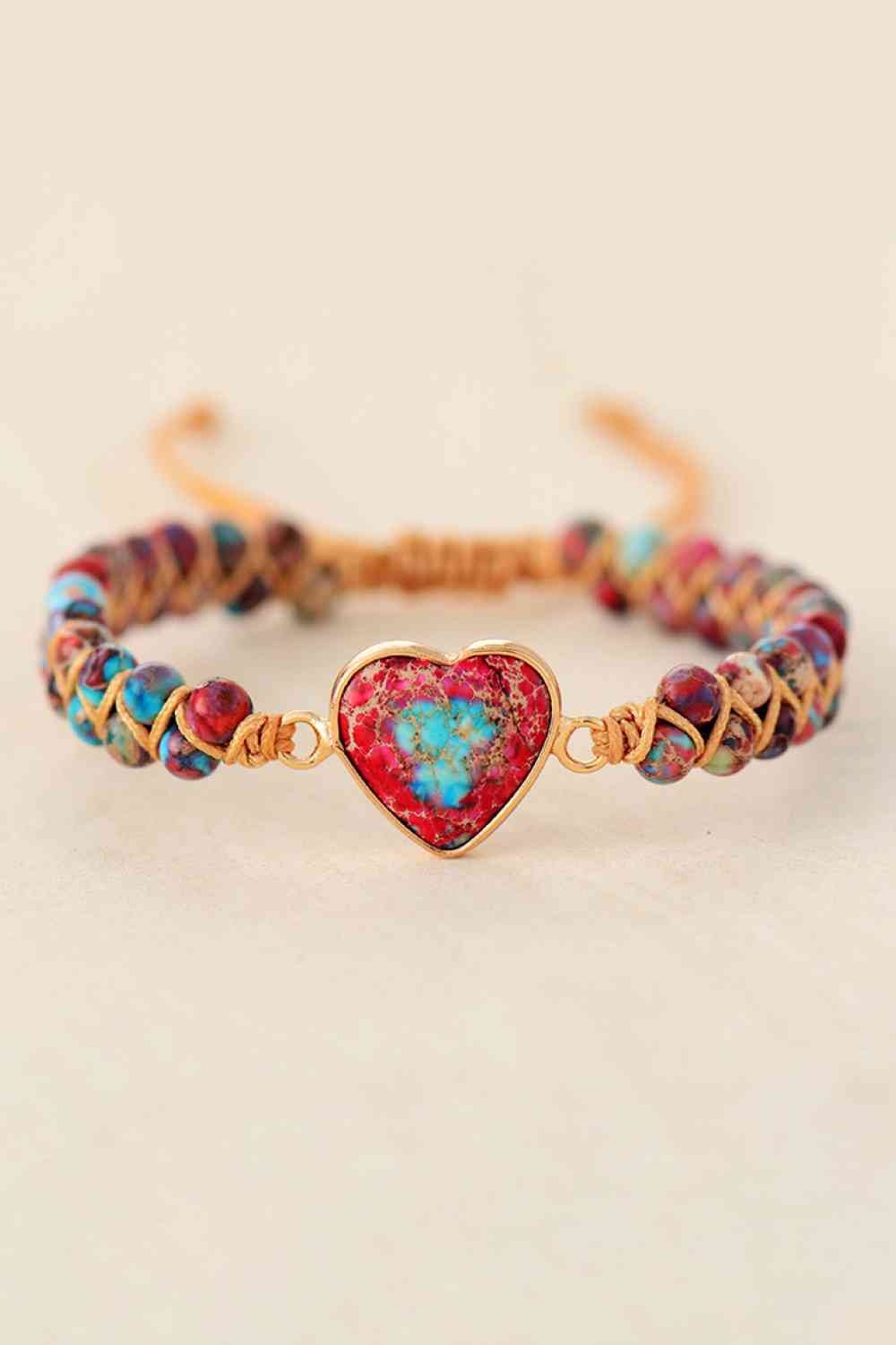 Handmade modern bracelet with a heart-shaped natural stone centerpiece in red, turquoise, and purple, framed by colorful beads and copper-toned woven detailing.