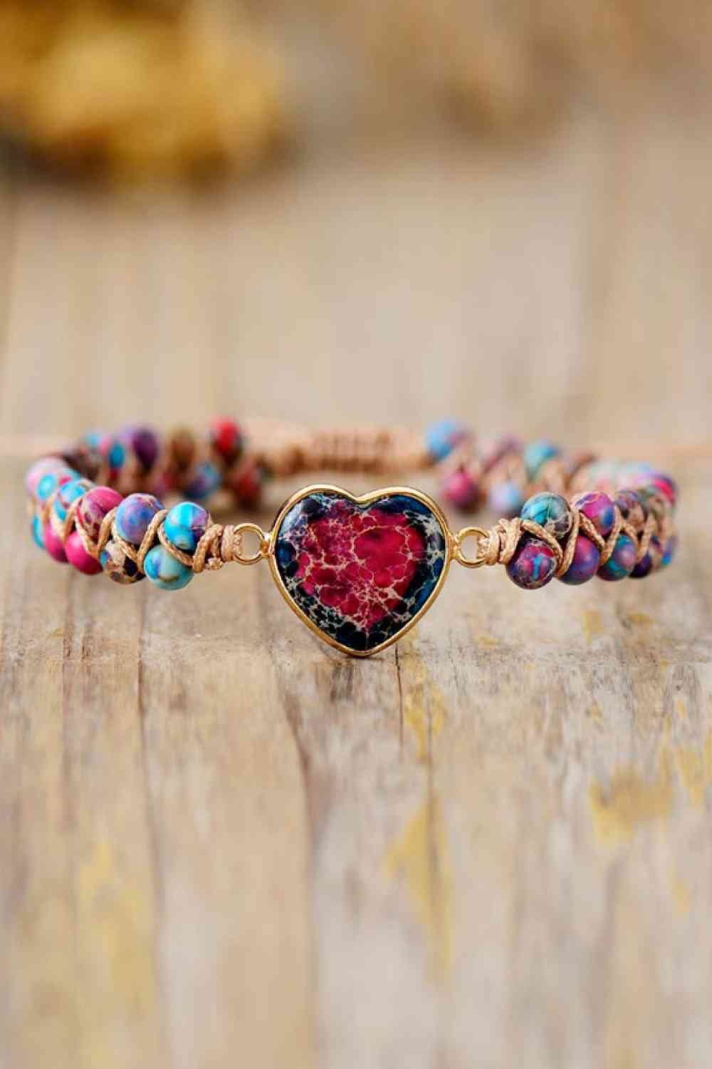 Handmade heart shape natural stone bracelet with colorful round beads, woven cord construction, and a marbled red-and-blue heart centerpiece in a copper-tone frame.