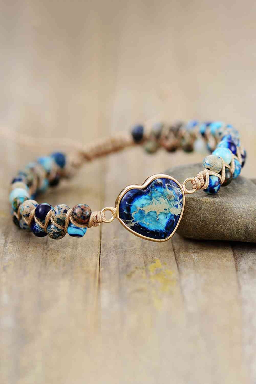 Handmade heart-shaped natural stone bracelet with a blue and turquoise marbled centerpiece, copper-toned setting, and braided cord accented by round stones.