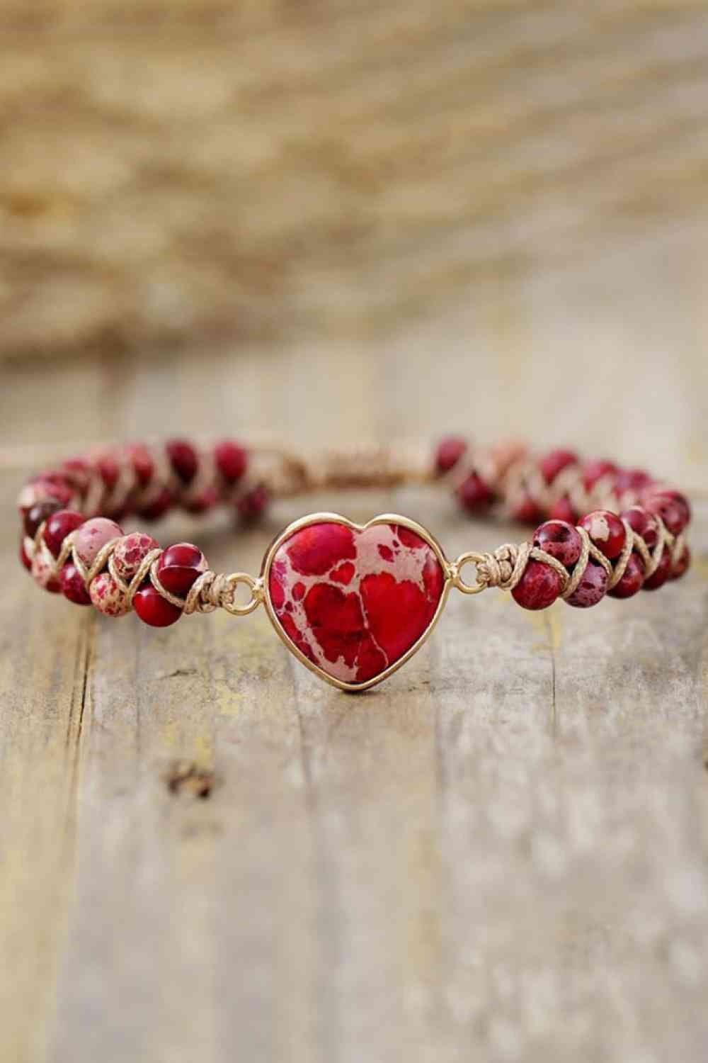 Handmade heart-shaped natural stone bracelet with a red and cream marbled stone centerpiece, copper-tone setting, and beaded braided chain.