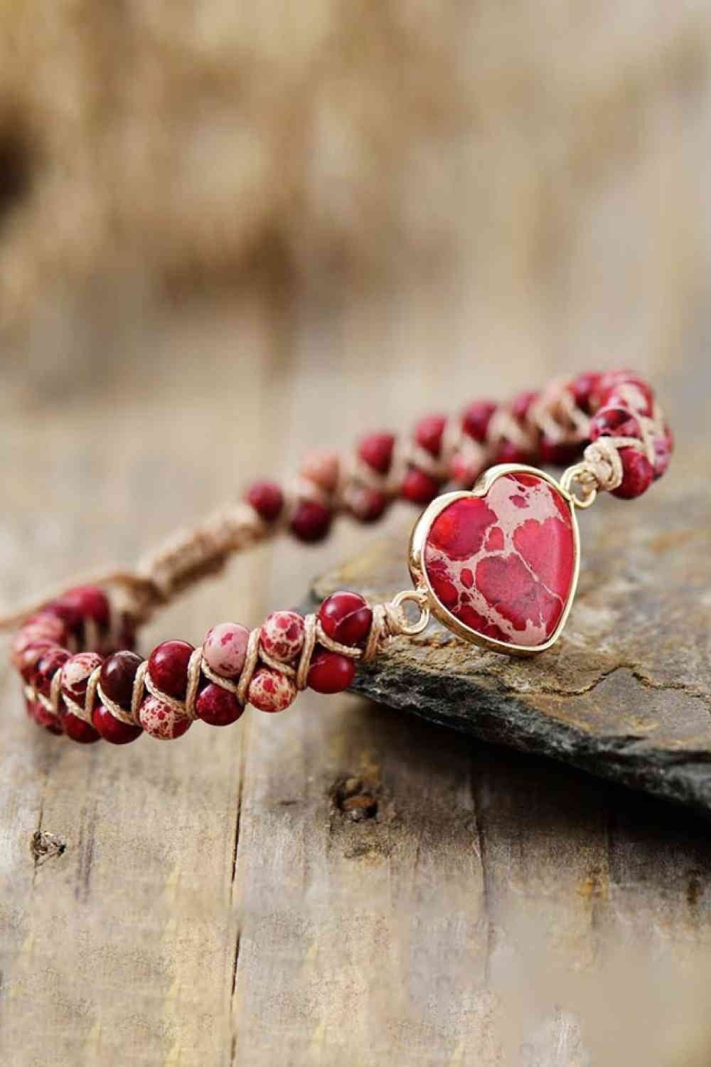 Handmade heart shape natural stone bracelet with red and pink beads, a marbled heart centerpiece in a copper-tone setting, and woven cord construction.