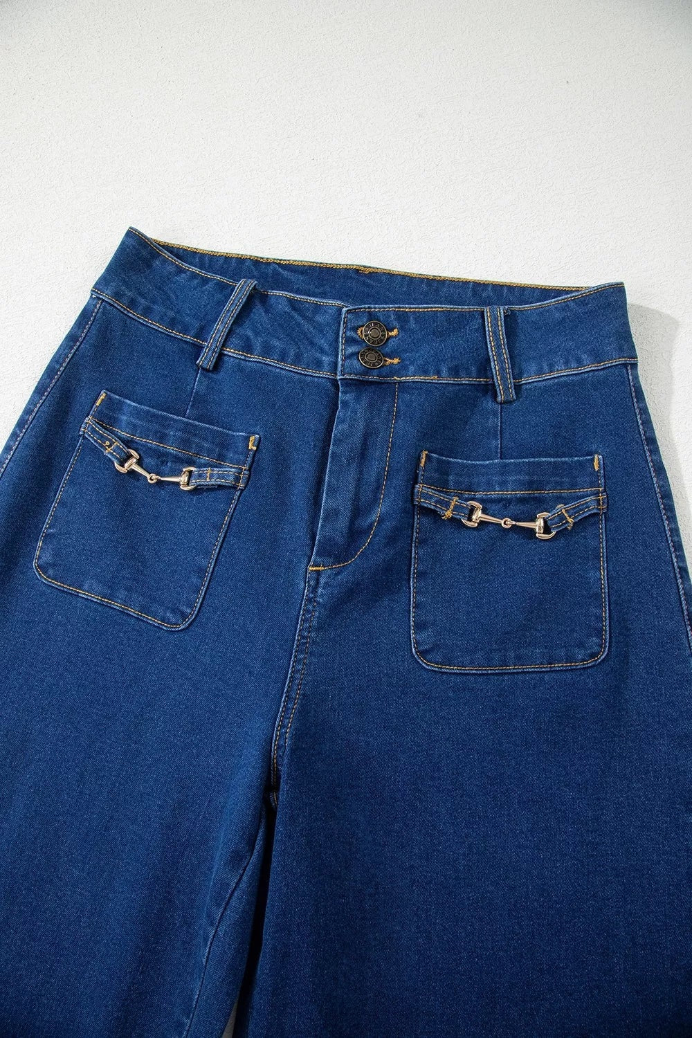 Deep blue wide-leg jeans feature large patched pockets with metal hardware accents, a button fly, belt loops, and contrasting topstitching.