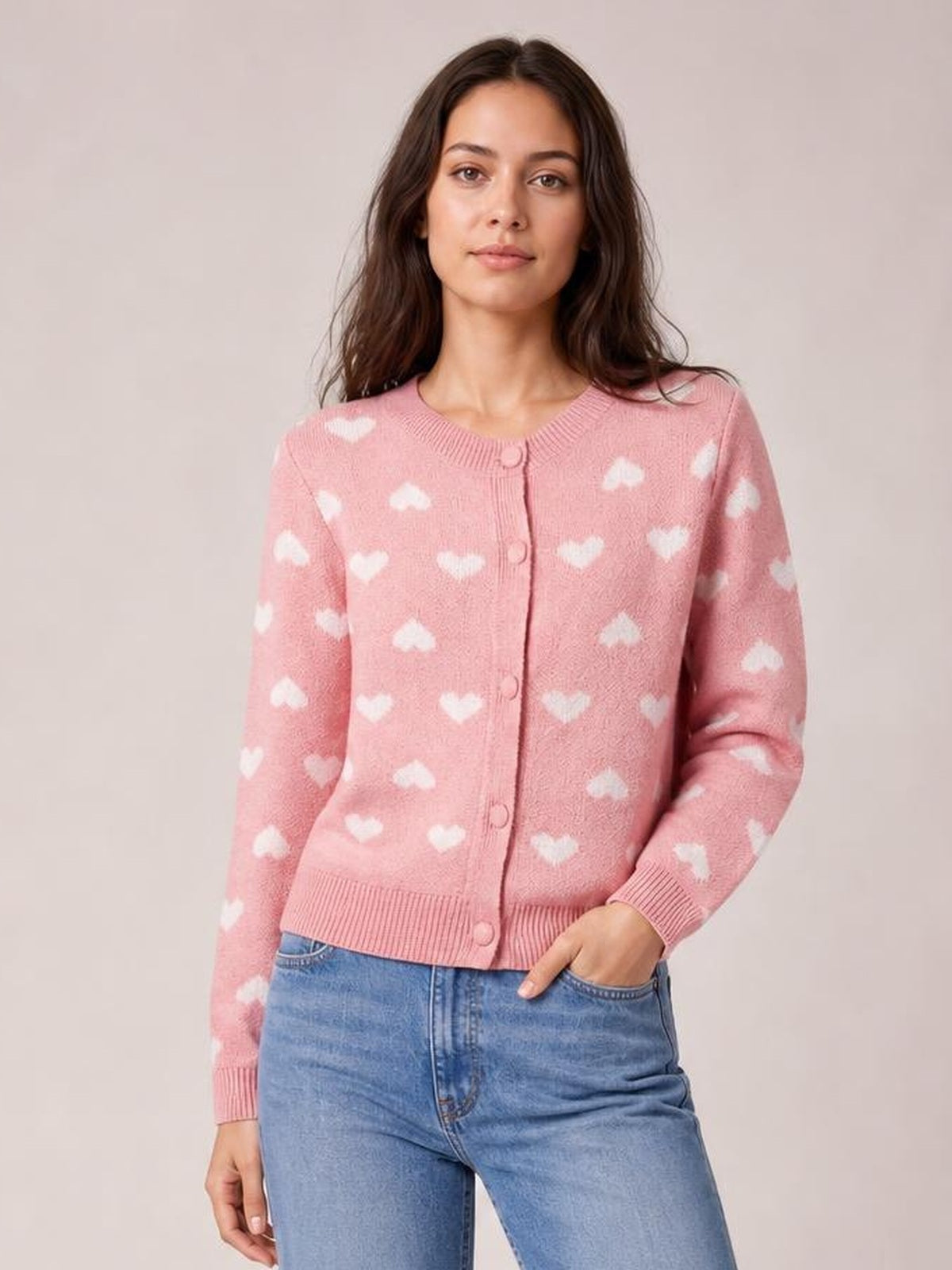 Model wearing a pink heart pattern button-front cardigan with long sleeves, ribbed neckline, cuffs and hem, and a fitted silhouette.