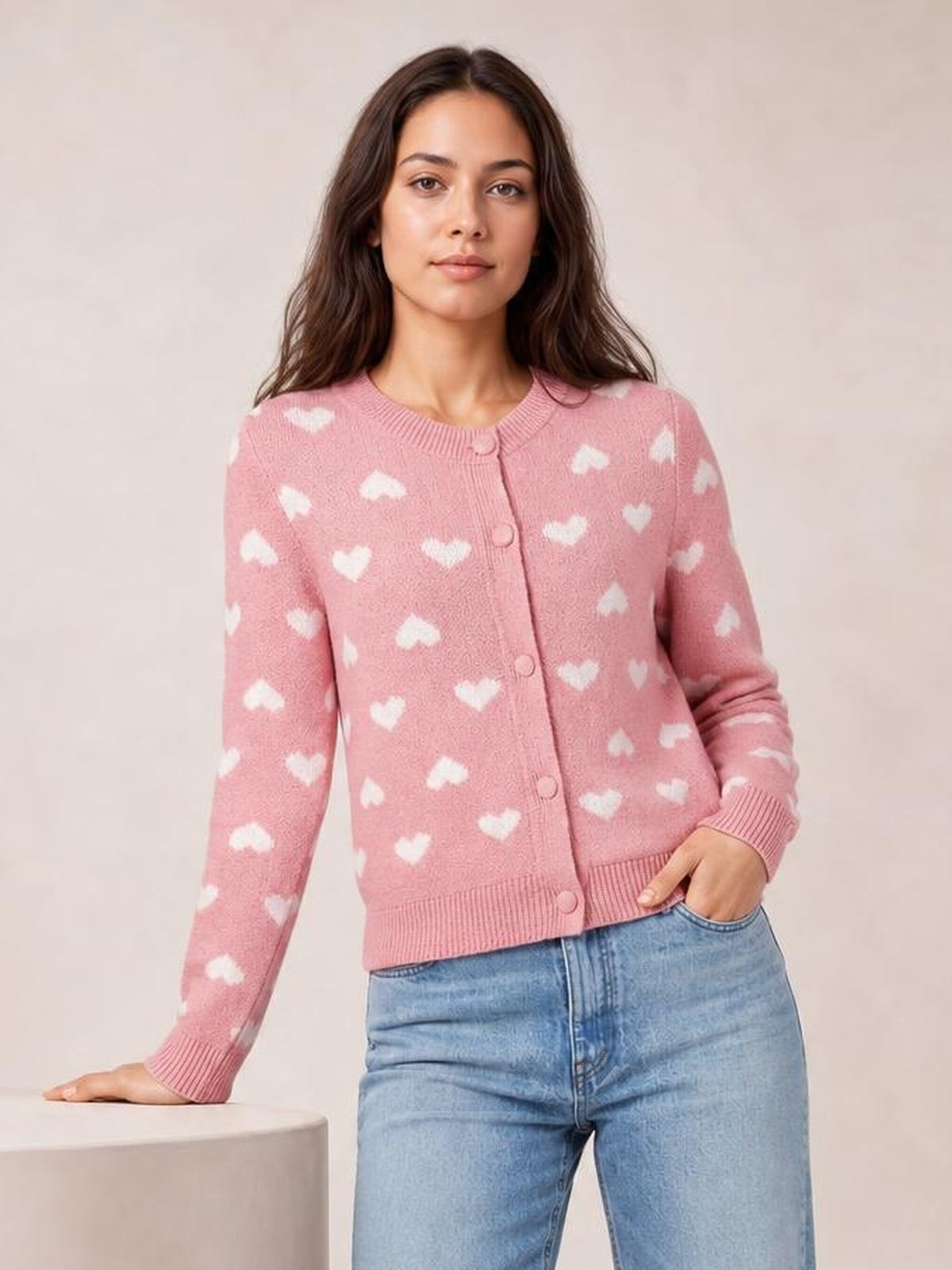 Model wears a pink heart pattern button-front cardigan with a round neckline, long sleeves, ribbed trim, and a fitted waist-length silhouette.