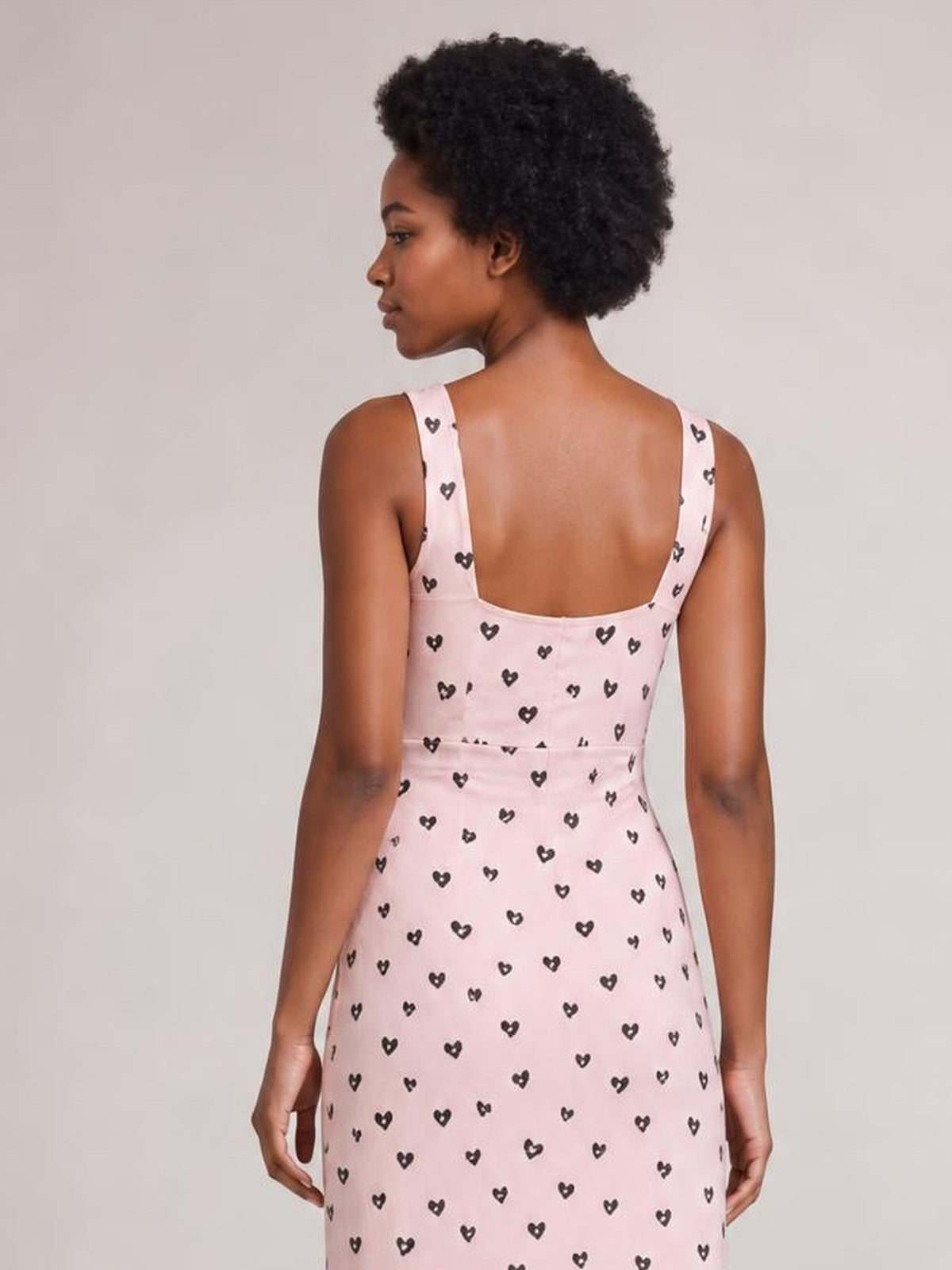 Model shown from behind wearing a pink heart-print midi dress with wide straps, a square open back, ruched waist, and fitted silhouette.