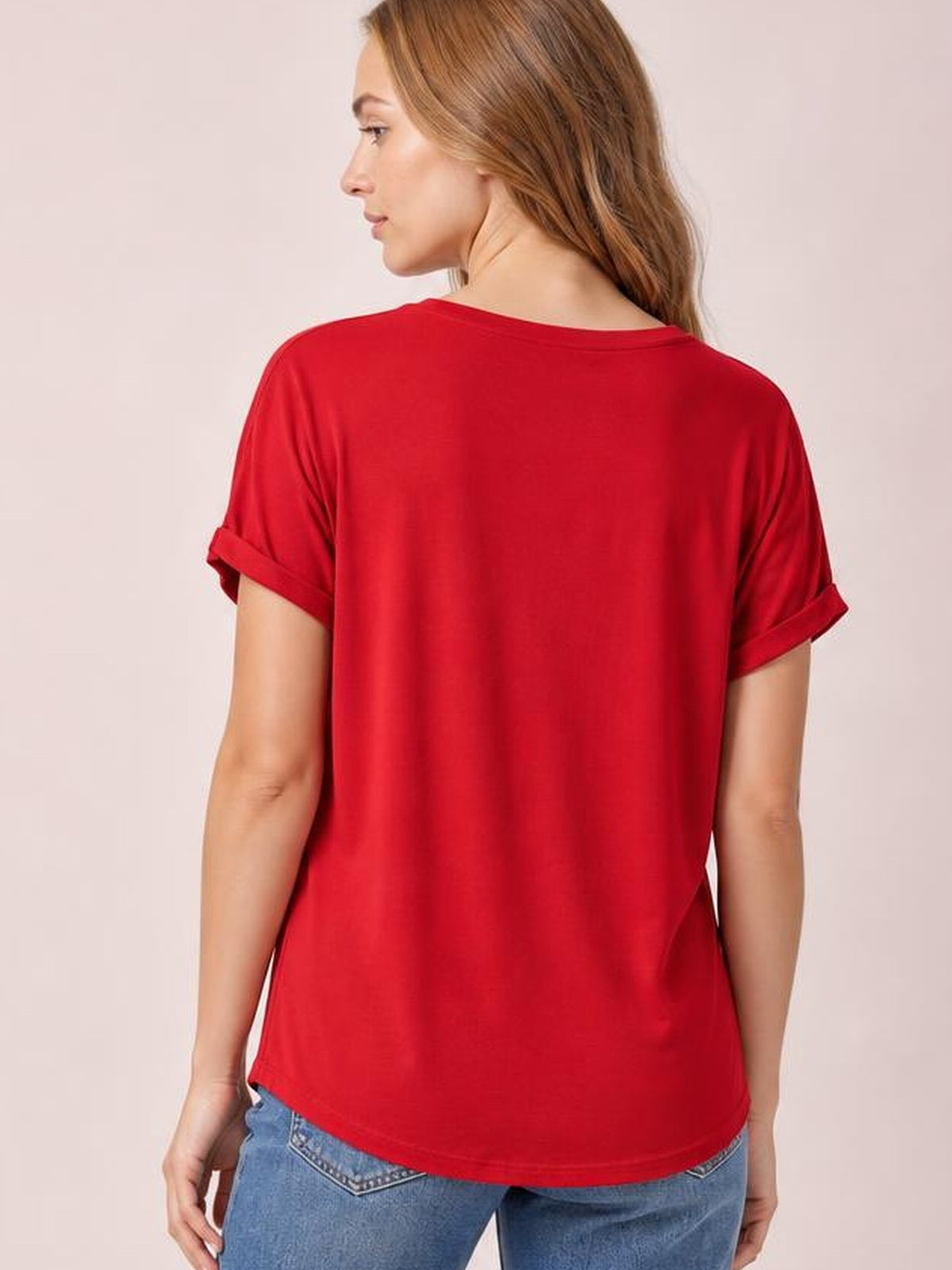 A model shown from behind wears a red round-neck short-sleeve T-shirt with rolled cuffs and a relaxed, straight silhouette over blue jeans.