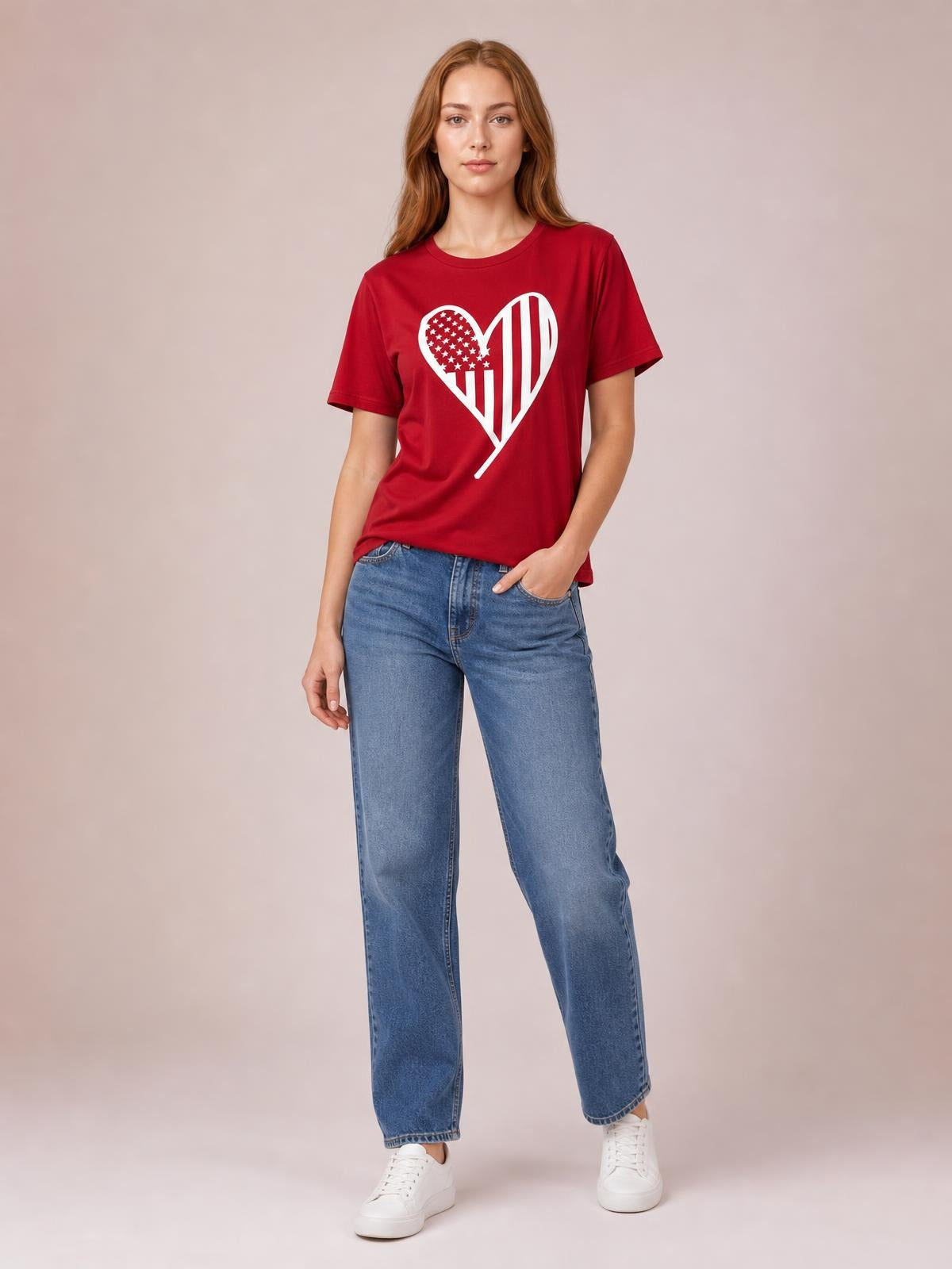 Model poses in a red heart graphic round-neck short-sleeve T-shirt with a relaxed straight silhouette, paired with jeans and one hand in a pocket.