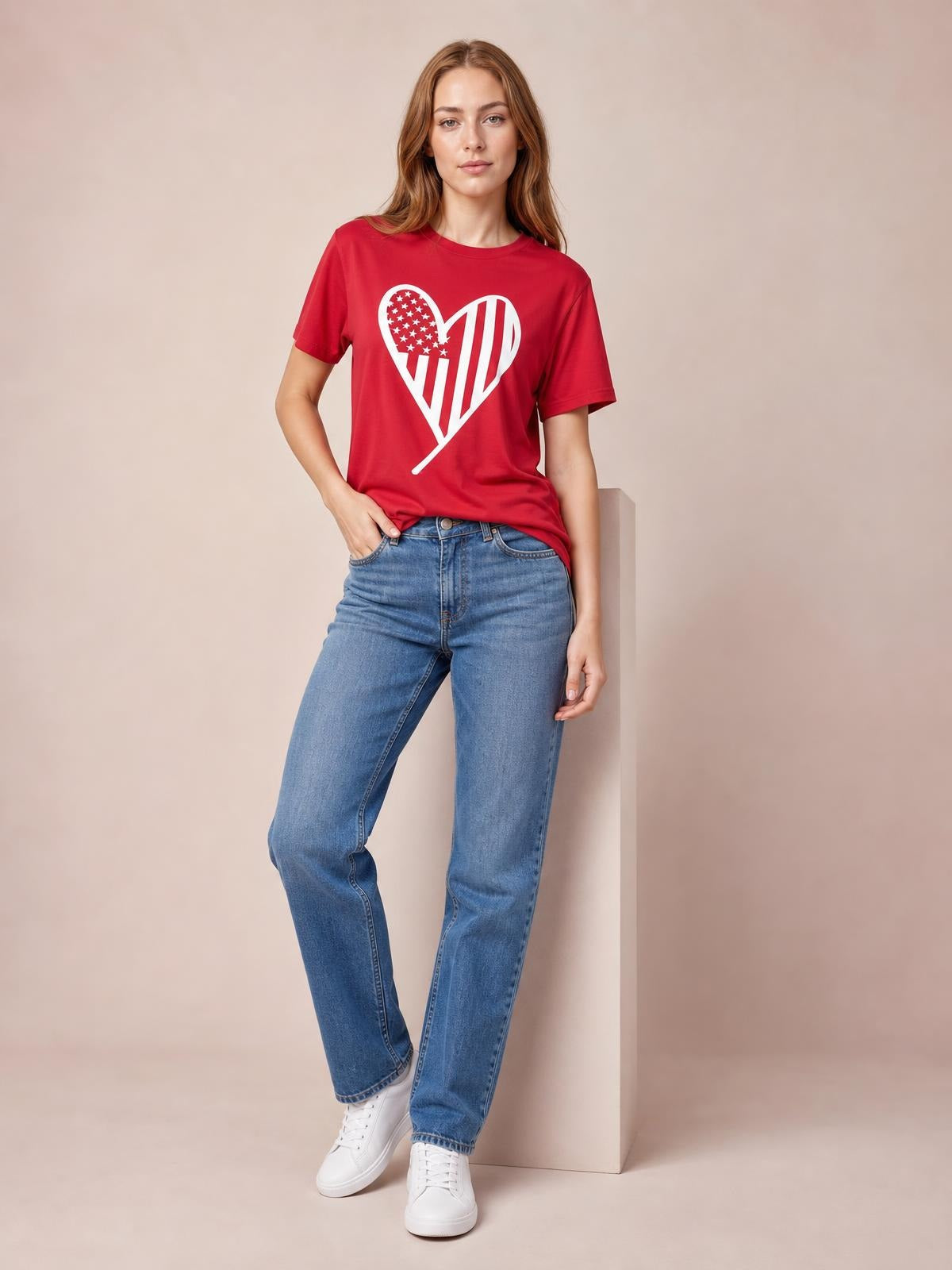 Model wears a red Heart Round Neck Short Sleeve T-Shirt with a bold white heart graphic, relaxed silhouette, and classic crew neckline, posing in jeans.