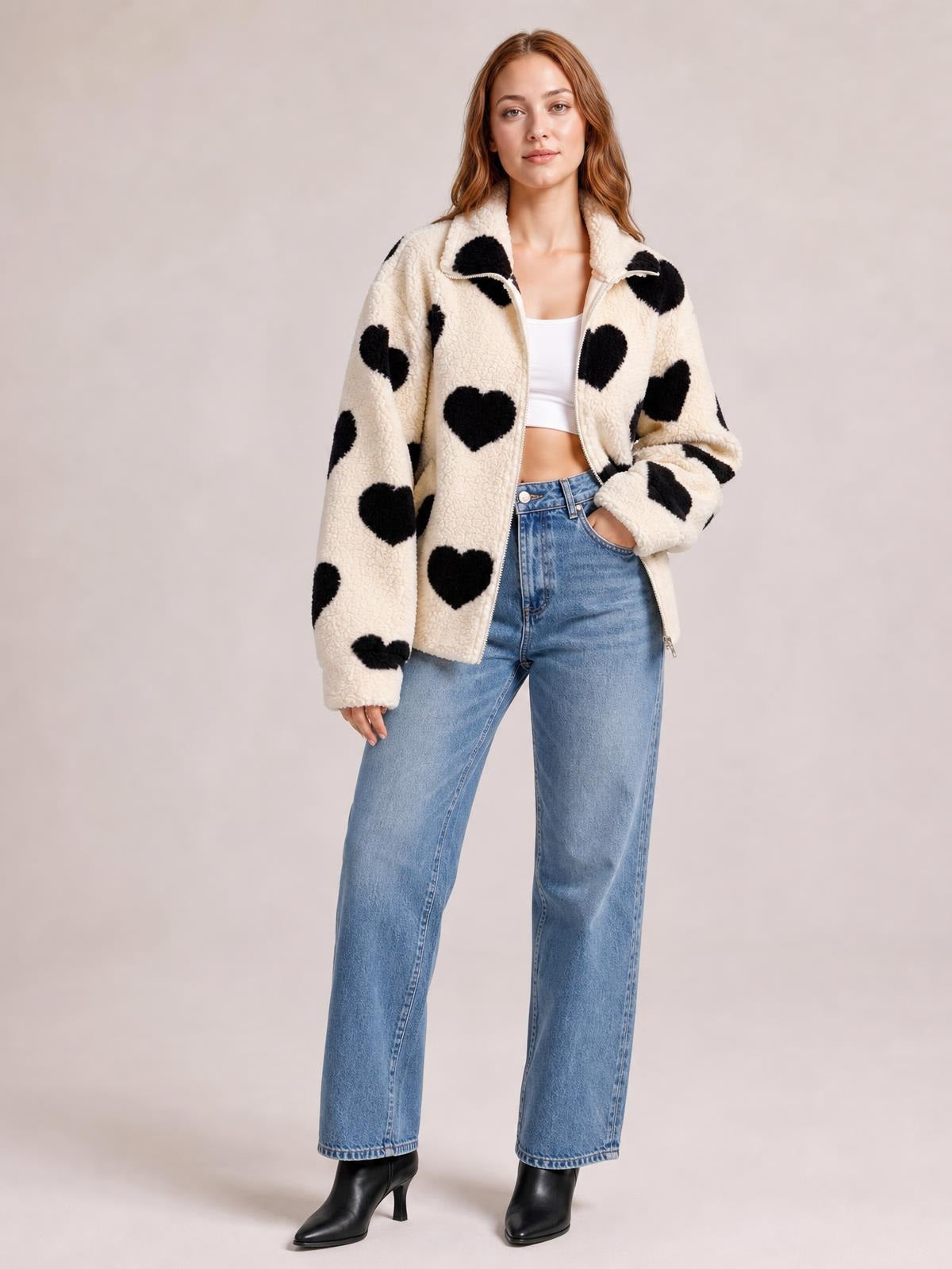 Model wears a cream furry heart zip-up jacket with black heart pattern, drop shoulders, a relaxed silhouette, and one hand tucked into the pocket.