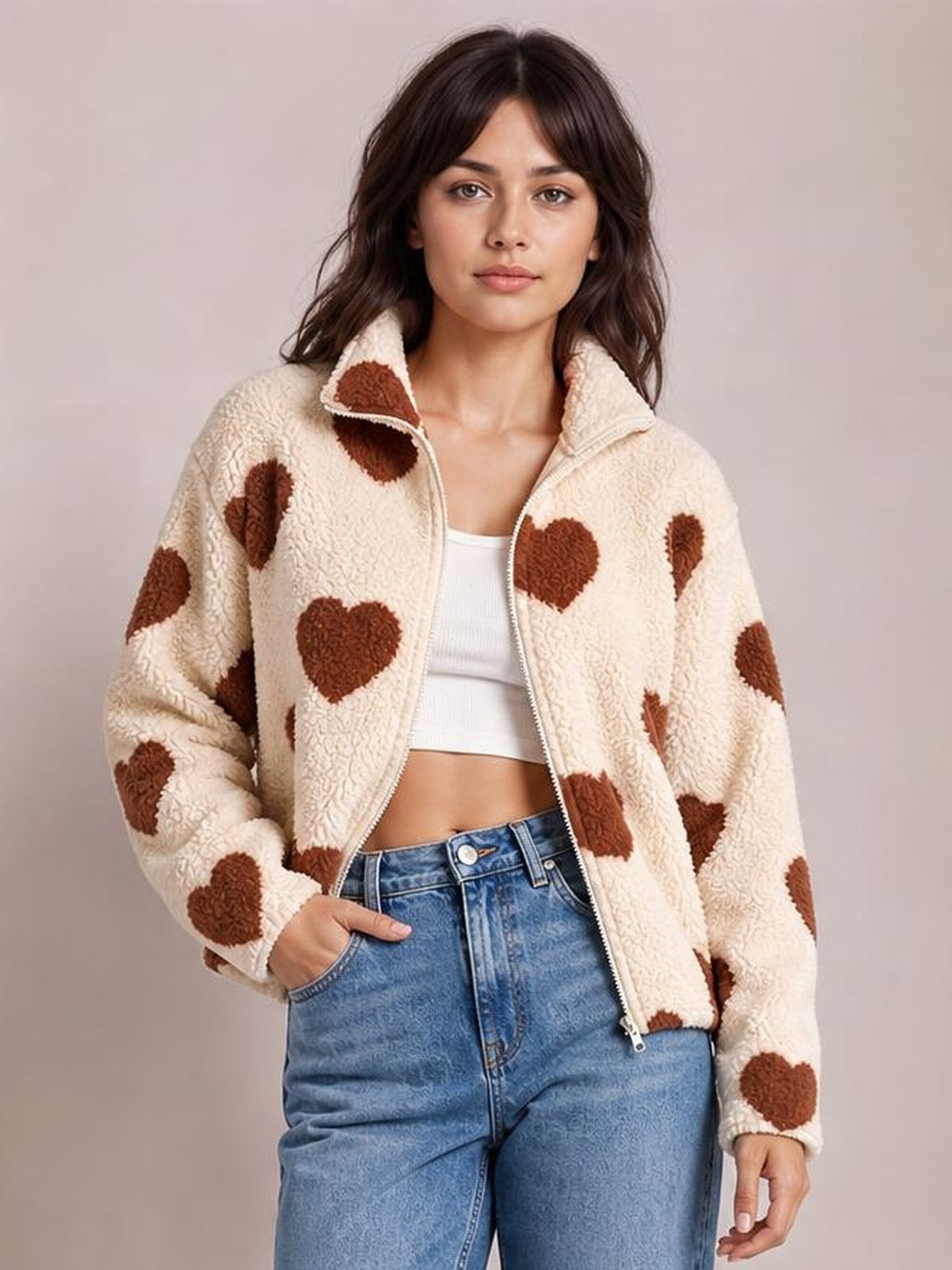 Model poses in a cream furry heart-print jacket with drop shoulders, a stand collar, zip front, relaxed silhouette, and one hand in a pocket.