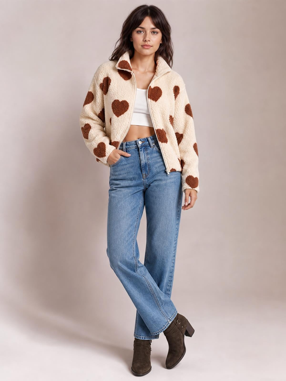 Model poses in an ivory furry heart-print jacket with a zip front, stand collar, drop shoulders, and relaxed silhouette worn open over a white crop top.