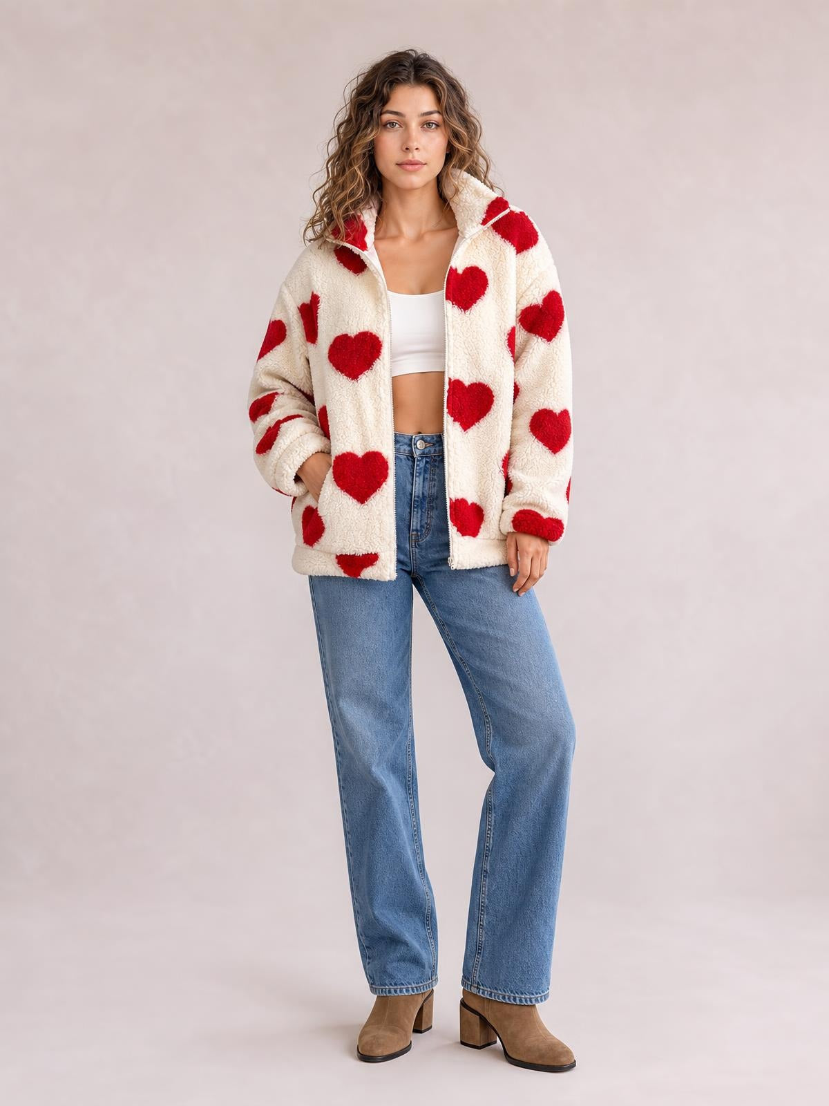 A model poses in a relaxed cream furry jacket with red heart print, zip-front closure, drop shoulders, long sleeves, and a loose silhouette.