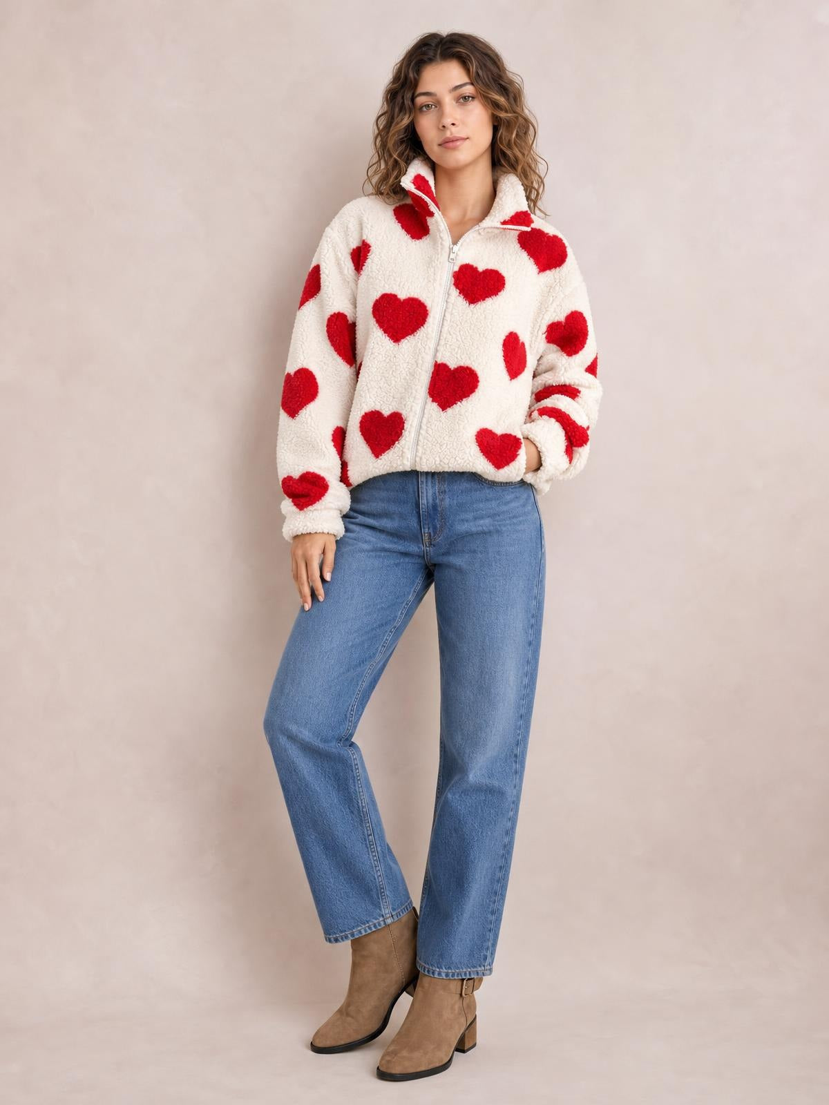 Model poses in a cream furry drop-shoulder jacket with red heart prints, zip front, stand collar, ribbed cuffs, and relaxed cropped silhouette.