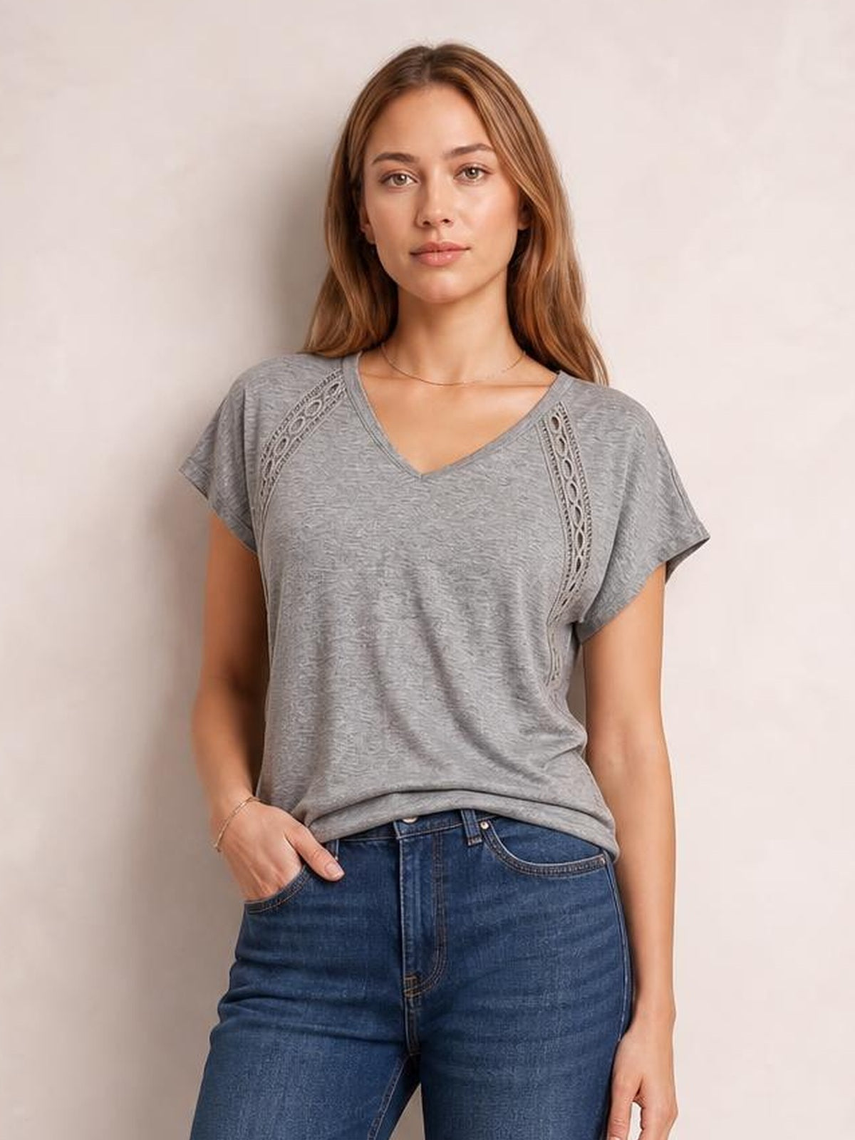 Model wears a heathered gray V-neck short-sleeve T-shirt with a relaxed silhouette and decorative eyelet panels along the shoulders.