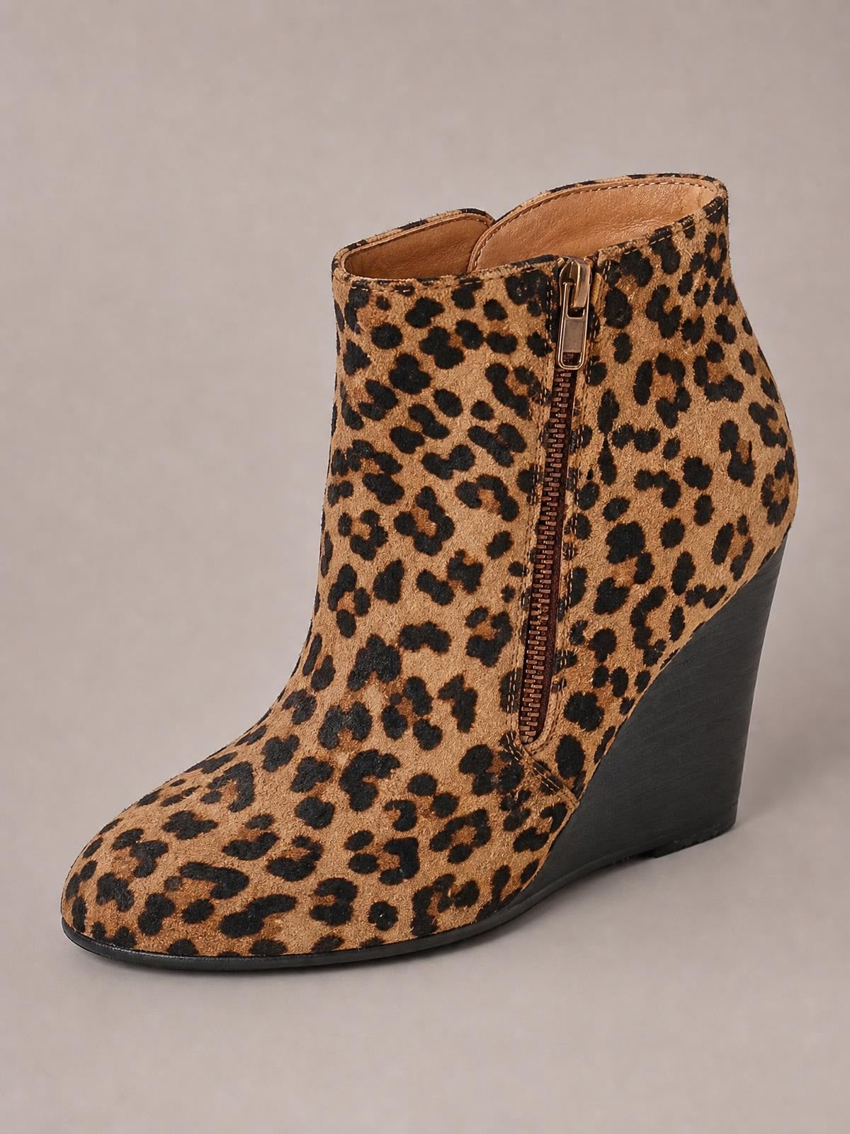 Leopard-print ankle boot with a rounded toe, tall black wedge heel, textured upper, and a visible side zip closure.