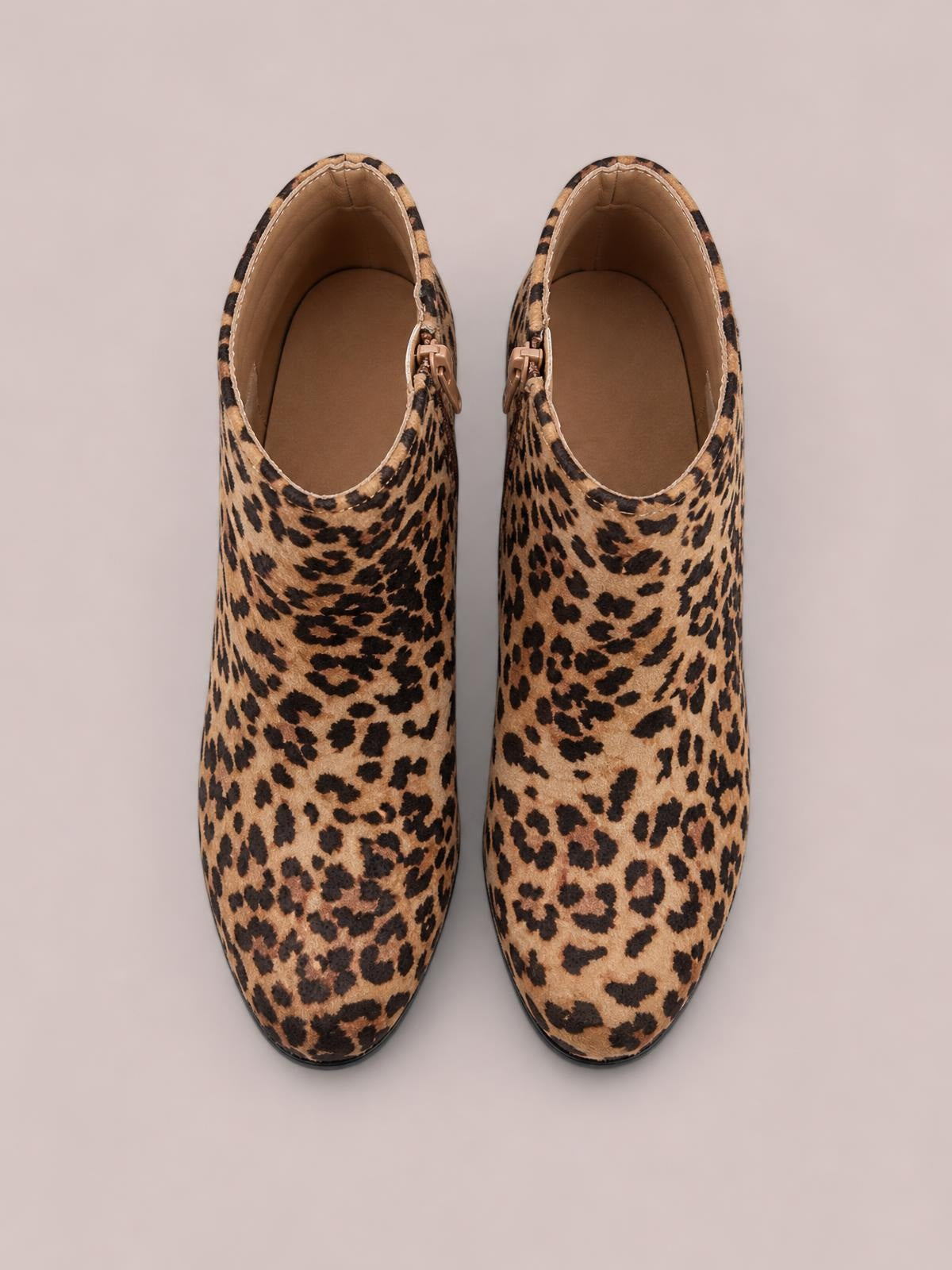Leopard-print ankle boots in tan and black feature rounded toes, structured shafts, side zippers, and high heels in a top-down view.