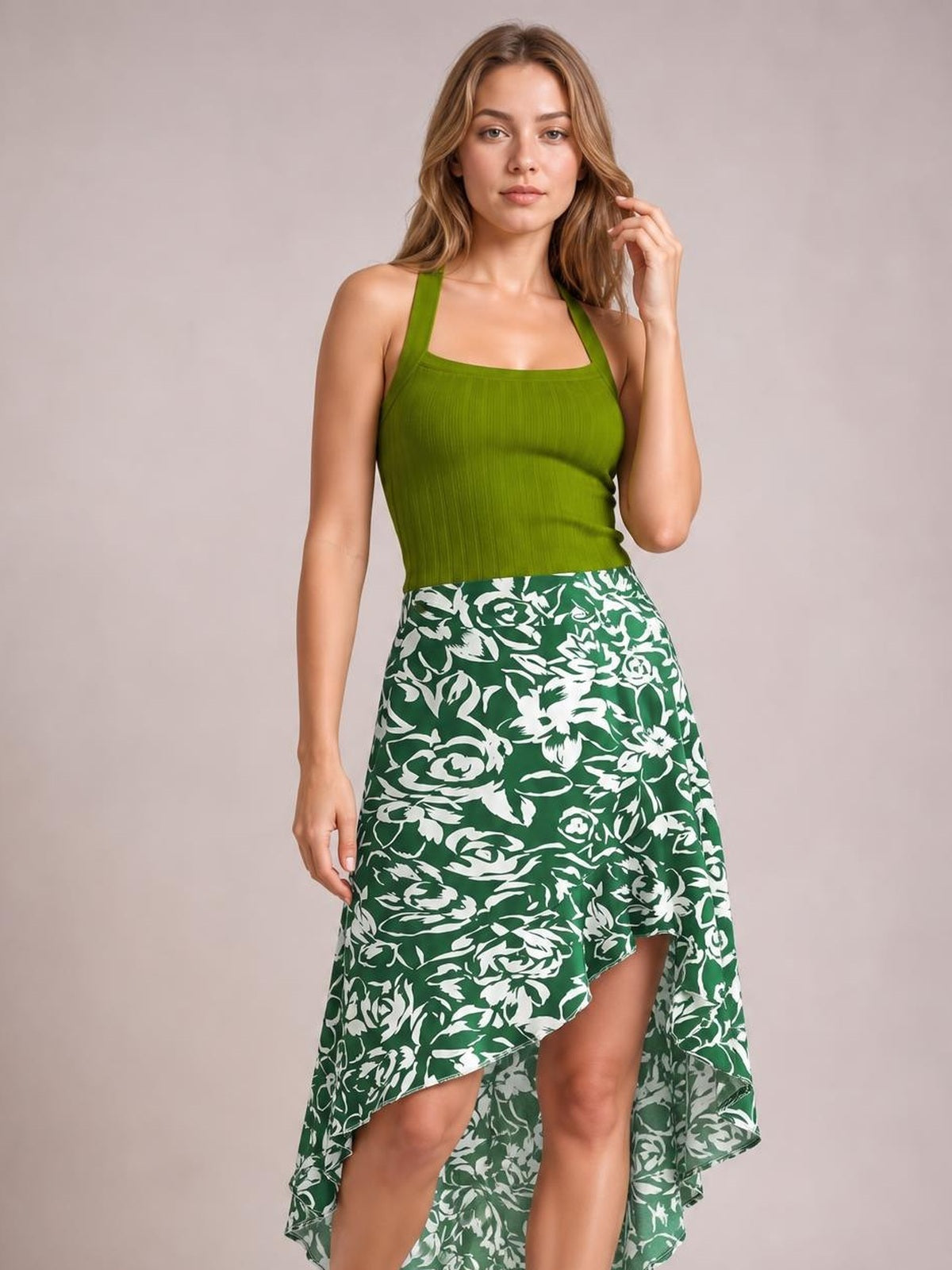 Model poses in a green and white floral printed high-waist skirt with an asymmetrical high-low hem and flowing silhouette.