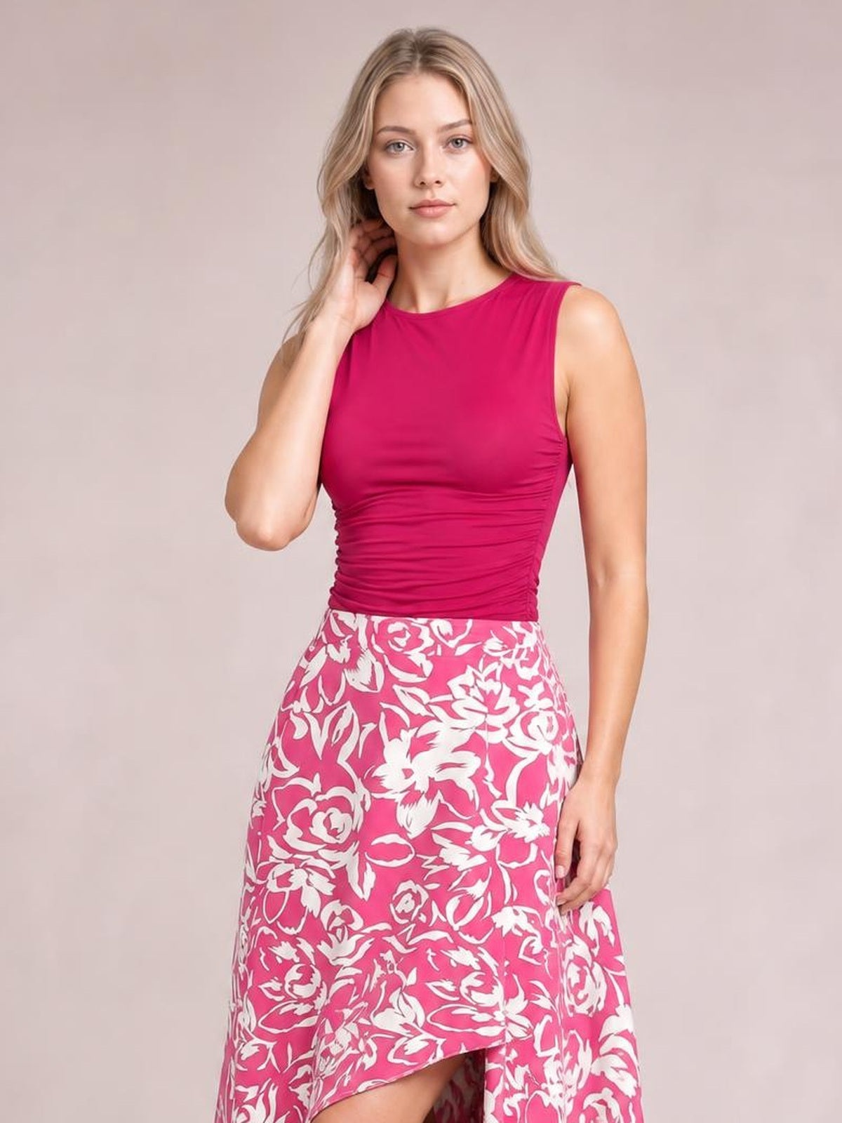 Model poses in a pink and white floral printed high-waist skirt with an asymmetrical high-low hem and flowing silhouette.
