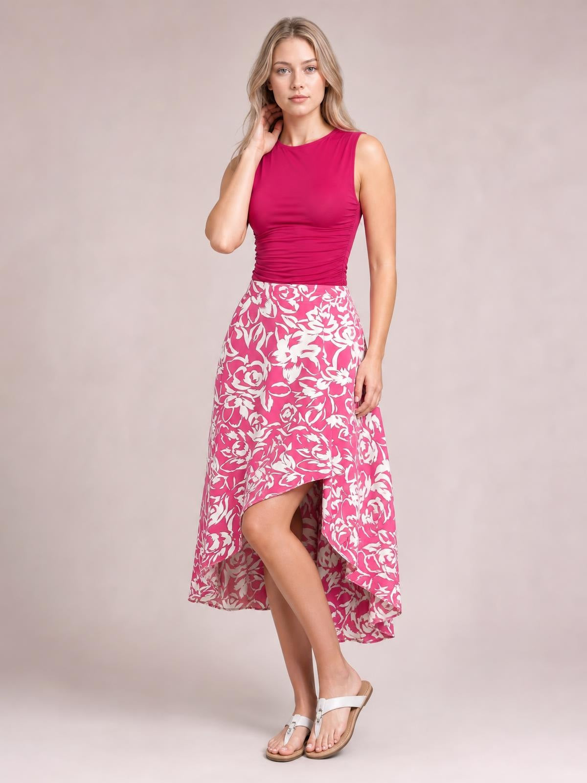 Model poses in a pink and white printed high-waist skirt with an asymmetrical high-low hem and flowing silhouette.
