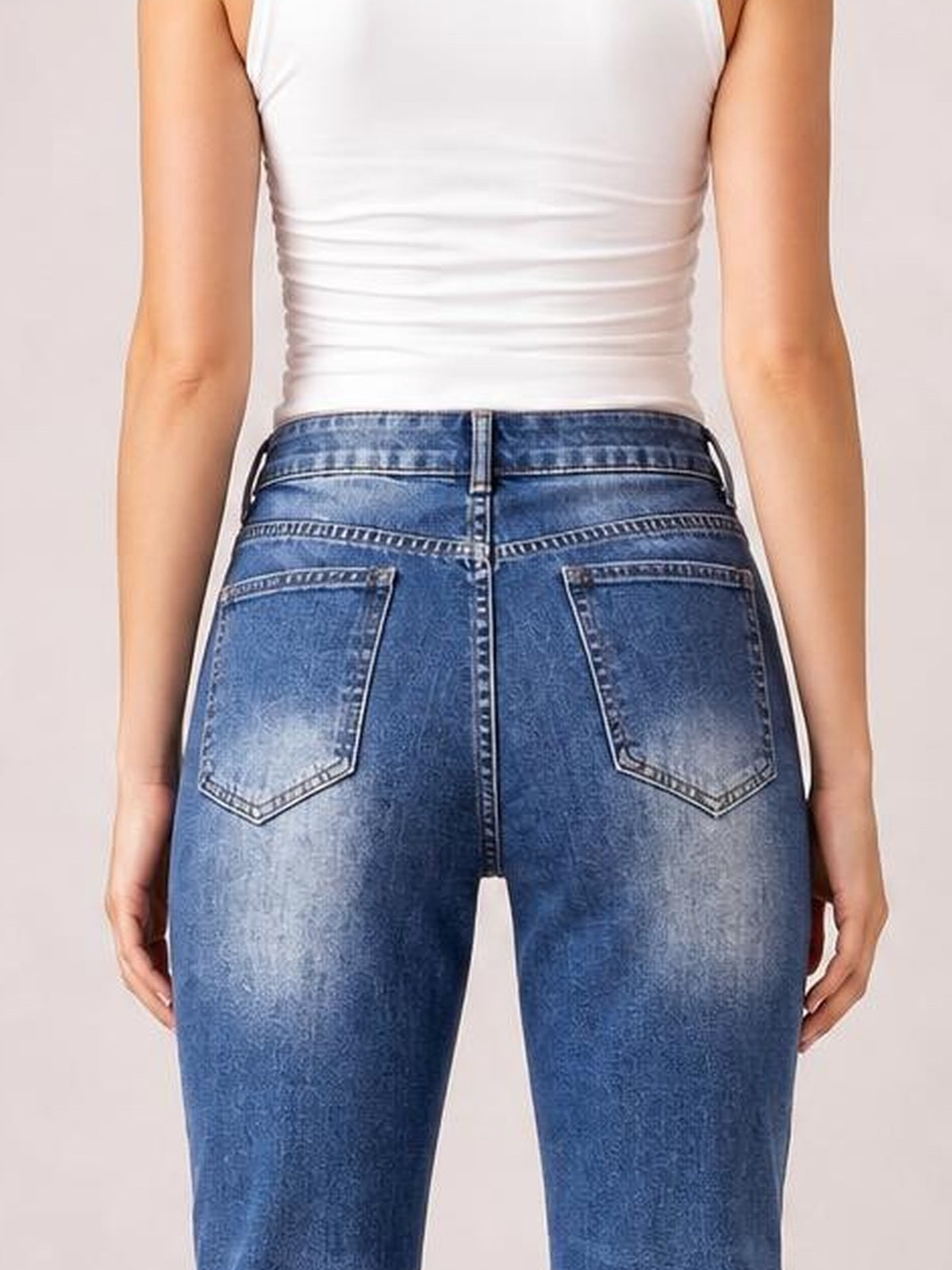 Model shown from behind wearing blue high-rise bootcut jeans with contrast stitching, belt loops, and two stitched back patch pockets.