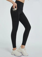 Model wearing black high waist active leggings with a fitted ankle-length silhouette, curved panel seams, and a side pocket holding a phone.