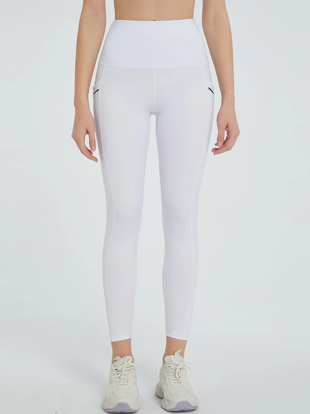 Model stands facing forward in white high-waist active leggings with a sleek fitted silhouette, moderate stretch, and visible side panel seams.