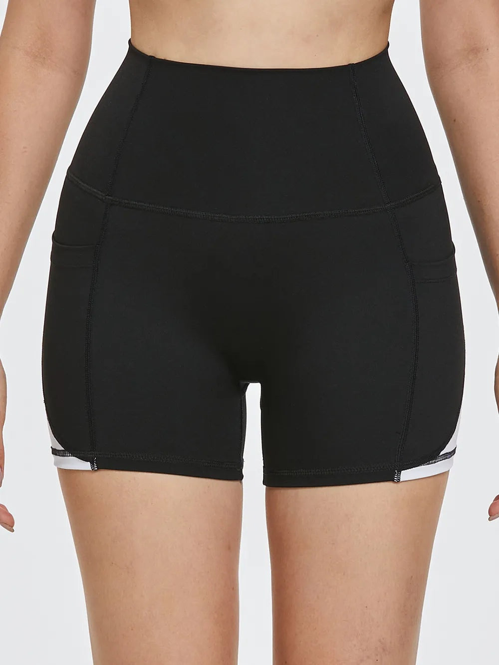 Model wears black high waist active shorts with a fitted silhouette, moderate stretch, curved seam construction, and mid-thigh length.