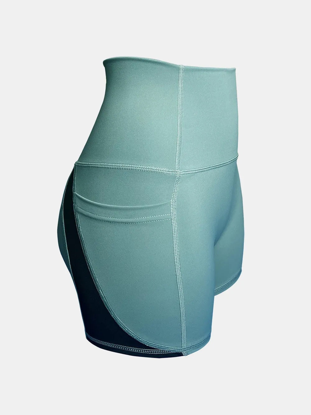 Sage green high-waist active shorts feature a fitted silhouette, wide waistband, curved side pocket, contrast dark side panel, and visible stitched seams.