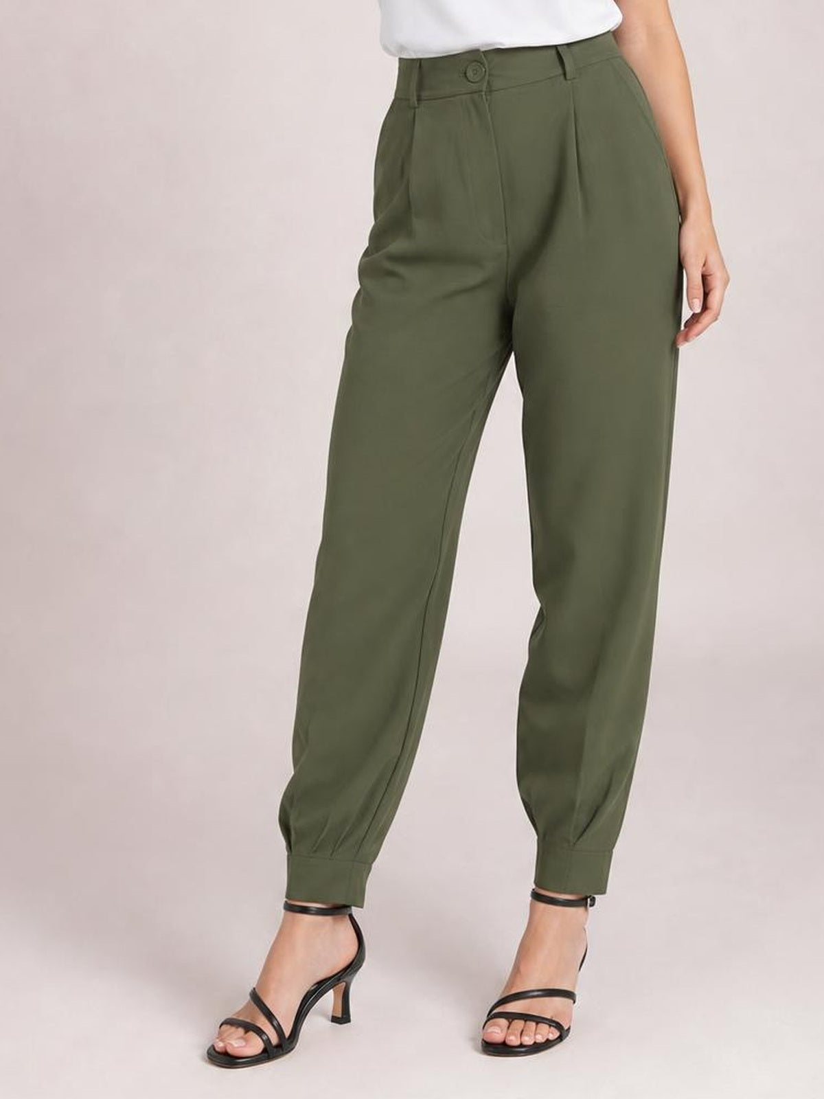 Model wears olive green high-waist cropped pants with a relaxed tapered silhouette, front button closure, side pockets, and gathered ankle cuffs.
