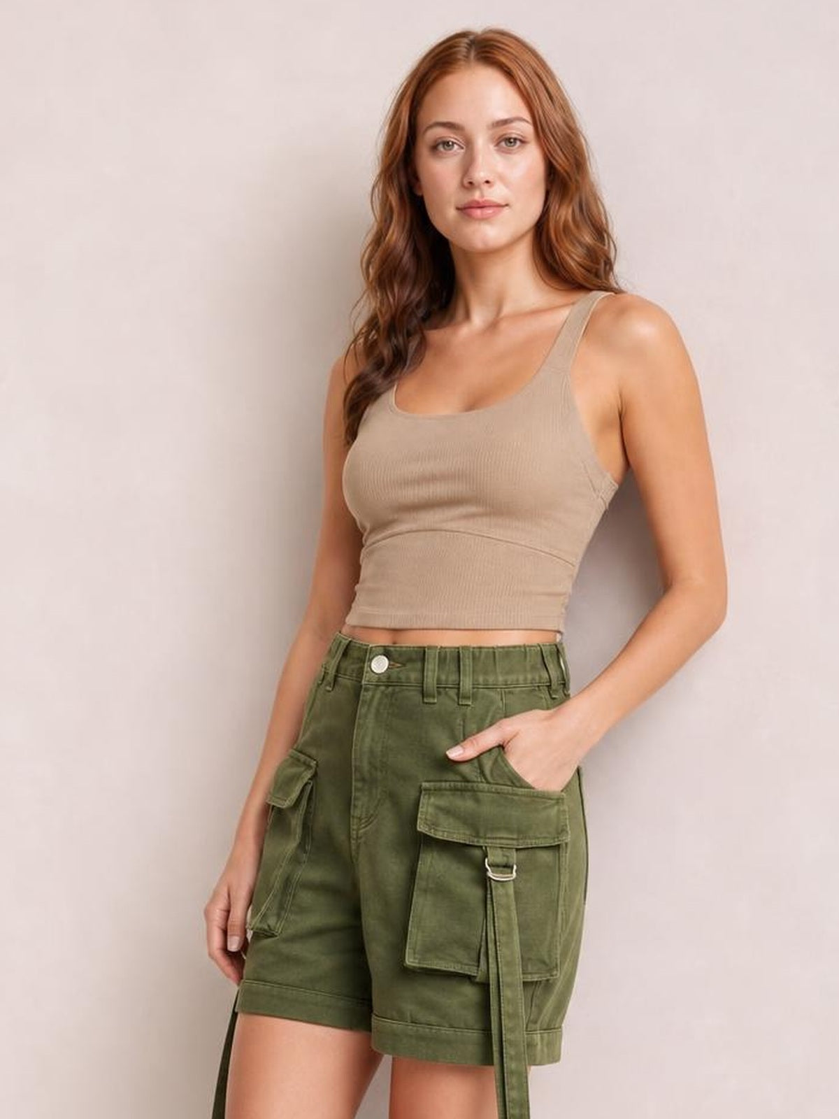 A woman modeling a beige ribbed scoop-neck crop top and olive green cargo shorts against a neutral light gray background.