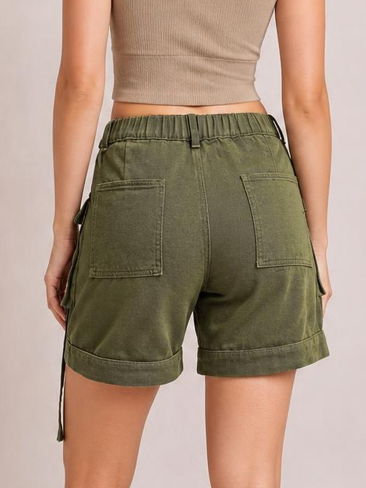 Model shown from behind wearing olive green high-waist denim cargo shorts with an elastic waistband, large patch pockets, relaxed fit, and cuffed hems.