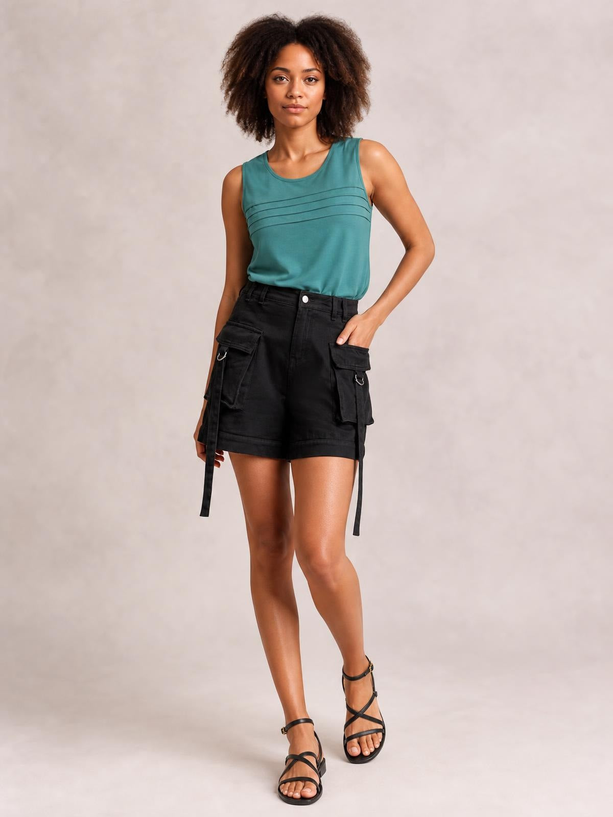 A model poses in solid black high-waist denim cargo shorts with a relaxed fit, flap pockets, belt loops, and long hanging utility straps.