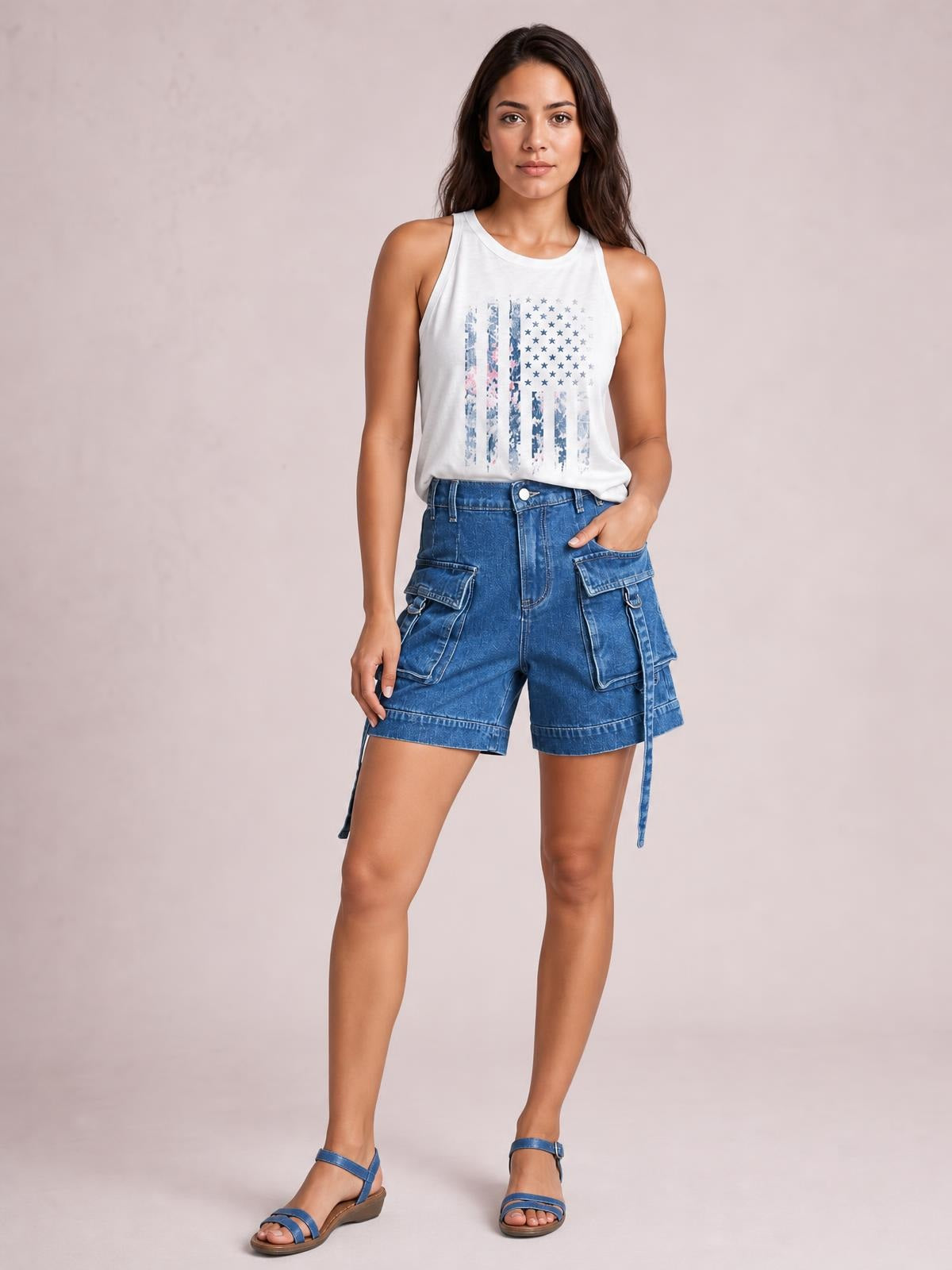 Model poses in blue high-waist denim cargo shorts with a structured relaxed fit, multiple flap pockets, belt loops, button closure, and cuffed hems.
