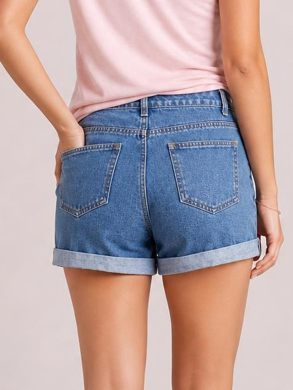 Model shown from the back wearing blue high-waist denim shorts with cuffed hems, belt loops, button closure, and two large back pockets.