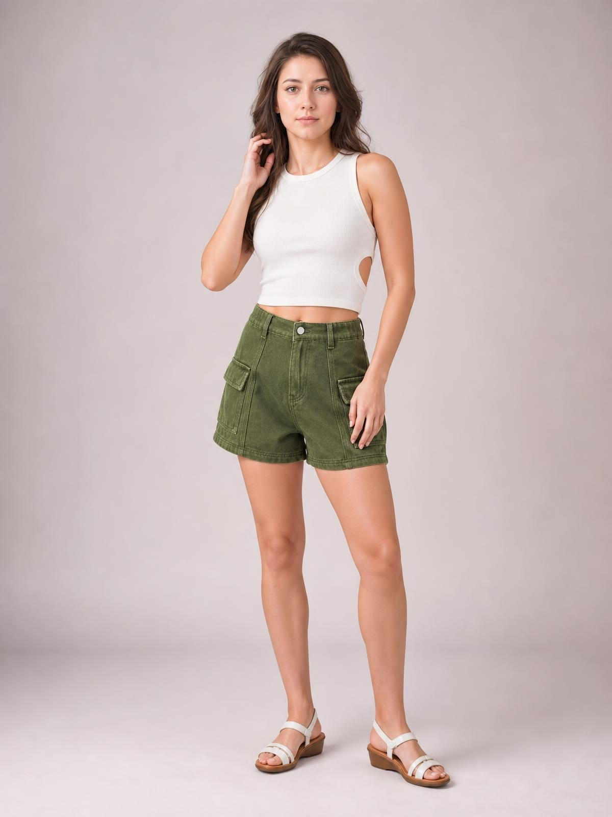 A model poses in olive green high-waist denim shorts with front cargo pockets, belt loops, button closure, seam details, and a relaxed straight-leg silhouette.