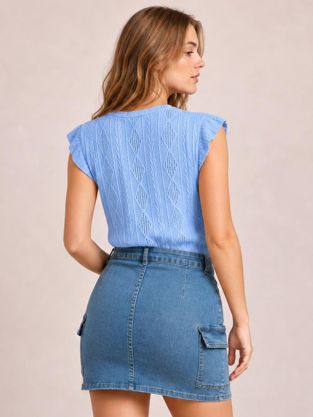 A model poses in a blue high-waist denim skirt with a fitted mini silhouette, center-back seam, belt loops, and practical patch pockets.