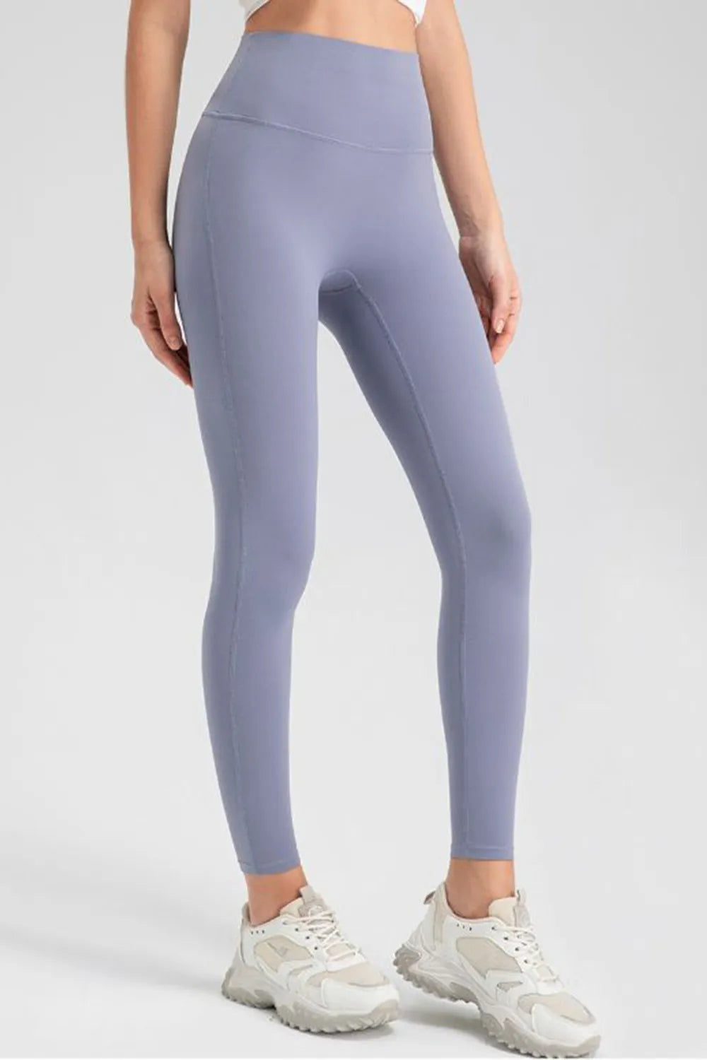 Model wears lavender high-waist skinny active pants with a smooth, stretchy leggings silhouette, seamed construction, and ankle-length tapered legs.