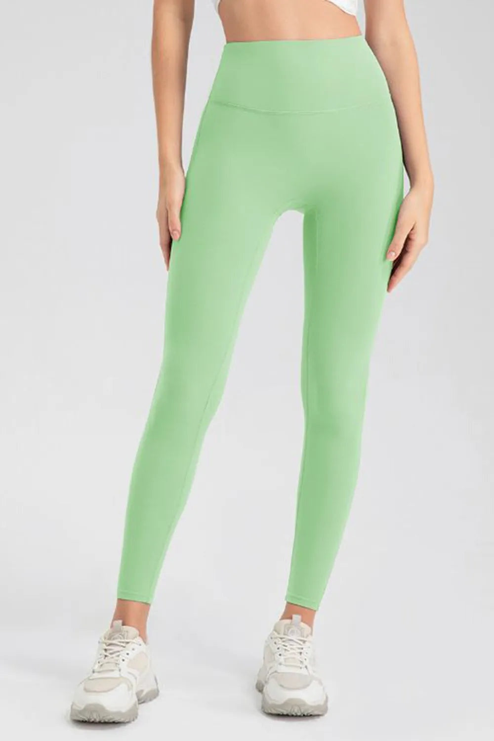 Model stands with hands at her sides wearing mint green high-waist skinny active pants with a smooth, stretchy, ankle-length silhouette.