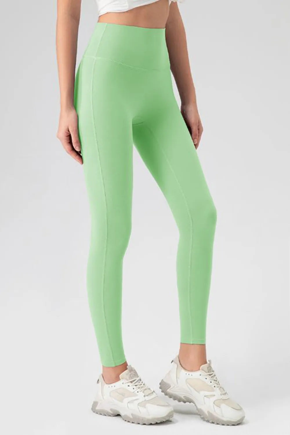 Model wears mint green high-waist skinny active pants with a fitted ankle-length silhouette, stretch construction, and visible seam detailing.