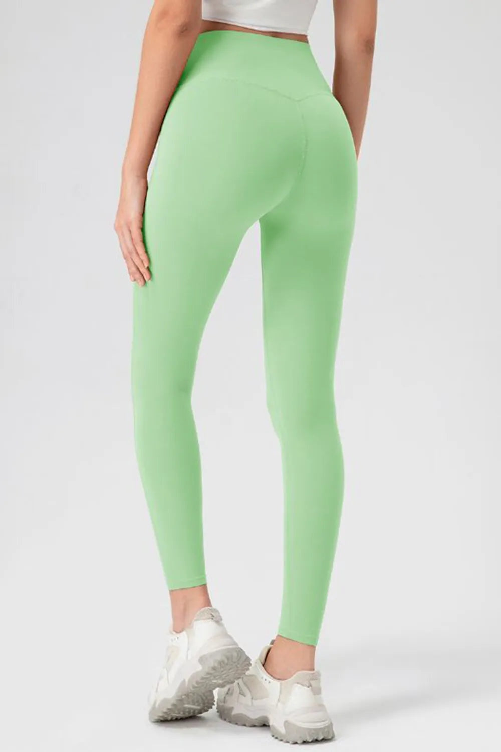 Model shown from behind wearing mint green high-waist skinny active pants with a sleek, stretchy ankle-length silhouette and visible center-back seam.