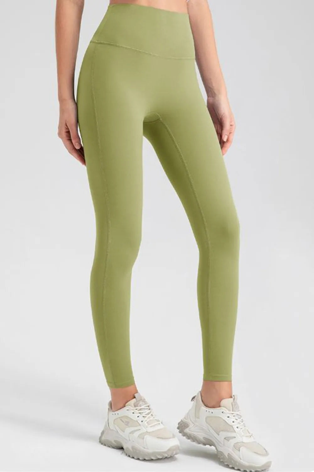Model stands in olive green high-waist skinny active pants with a smooth fitted silhouette, wide waistband, and visible front and side seams.