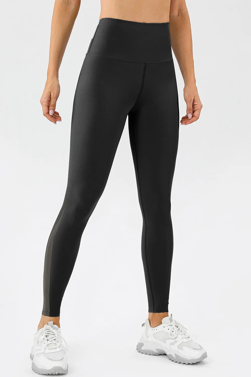 Model wears black high-waist skinny active pants with a wide waistband, sleek fitted silhouette, and ankle-length construction.