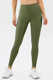 Model wears olive green high-waist skinny active pants with a wide contoured waistband, smooth stretch construction, and ankle-length fitted legs.