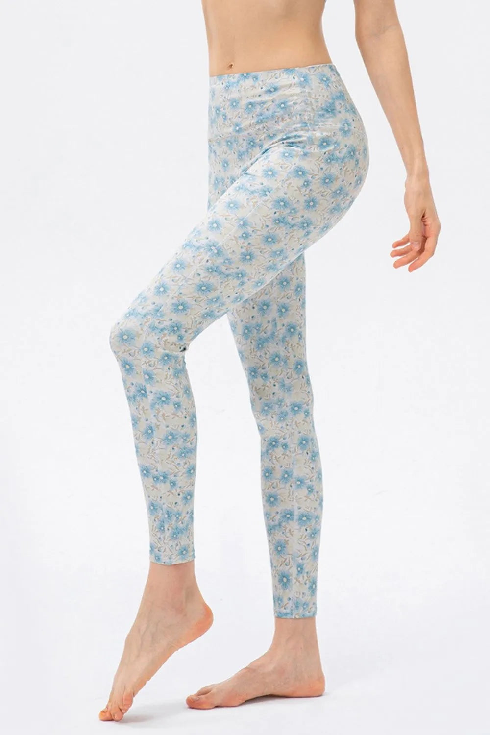 Model poses in high-waisted skinny active leggings with a fitted ankle-length silhouette, blue floral print, and moderate-stretch construction.