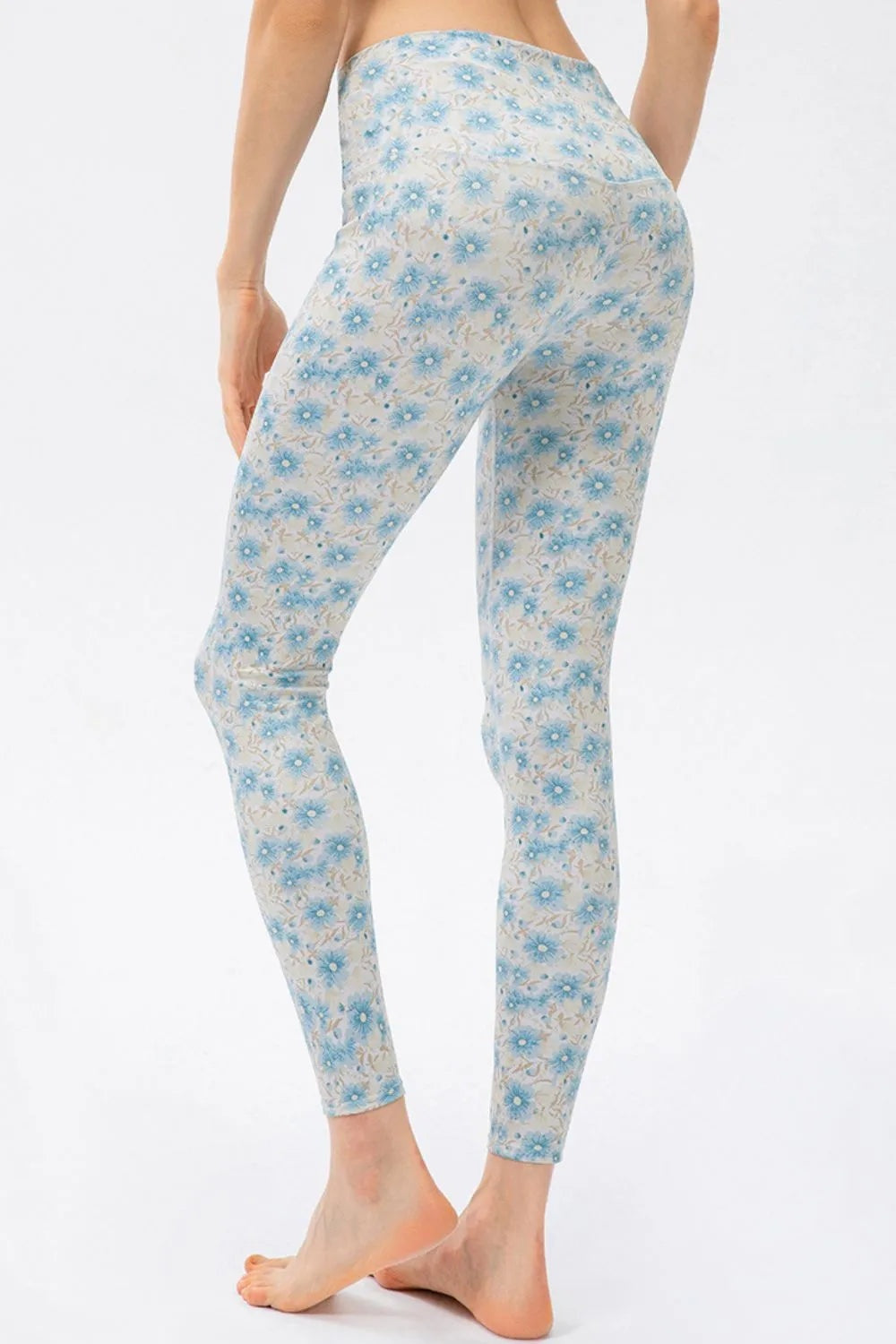 Model wears high-waist skinny active pants with a fitted ankle-length silhouette, moderate stretch, and a delicate blue floral print on a white base.