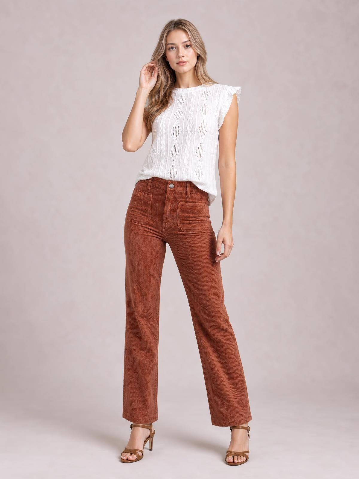 A model poses in rust-brown high-waist corduroy pants with square front pockets, belt loops, button closure, and a relaxed straight-leg silhouette.