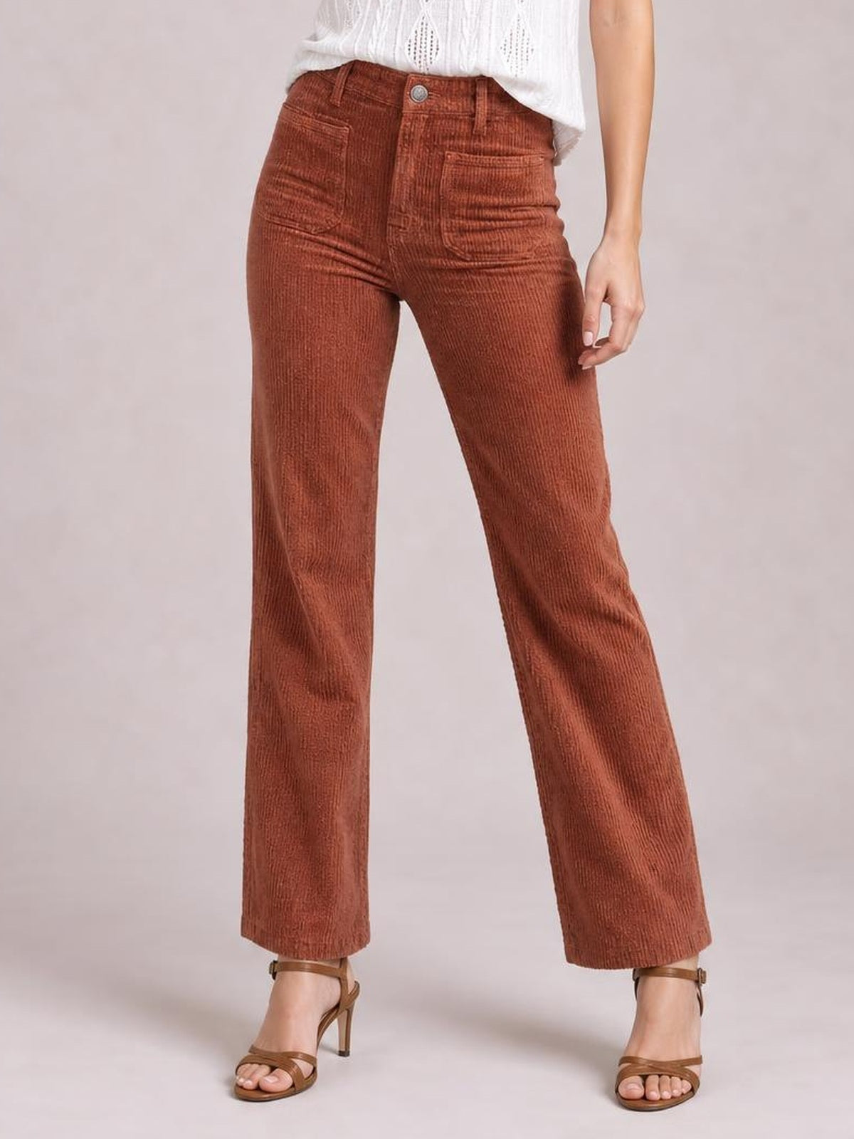 Model wears high-waist rust-brown corduroy pants with square front pockets, belt loops, button closure, and a straight-leg silhouette.