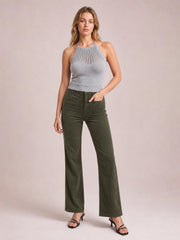 A model wears olive high-waist corduroy pants with square front pockets, a fitted seat, and a long, wide-leg silhouette while standing with one hand in a pocket.