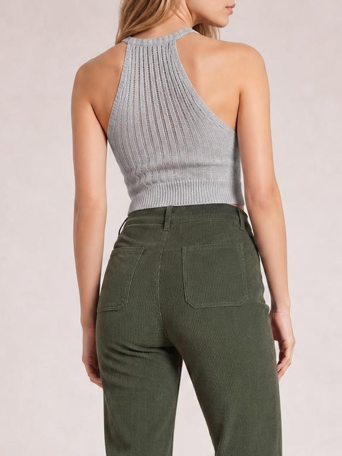 Model shown from behind in olive green high-waist corduroy pants with belt loops, square patch pockets, a fitted hip, and straight legs.